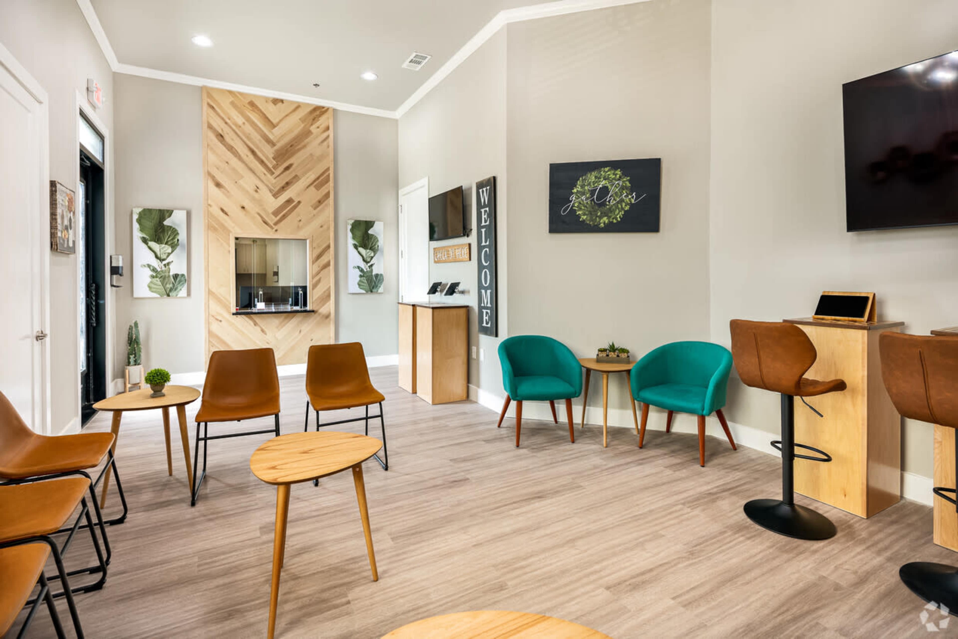 A modern waiting area with brown and teal chairs, small wooden tables, and a decorative wall with a welcoming sign.