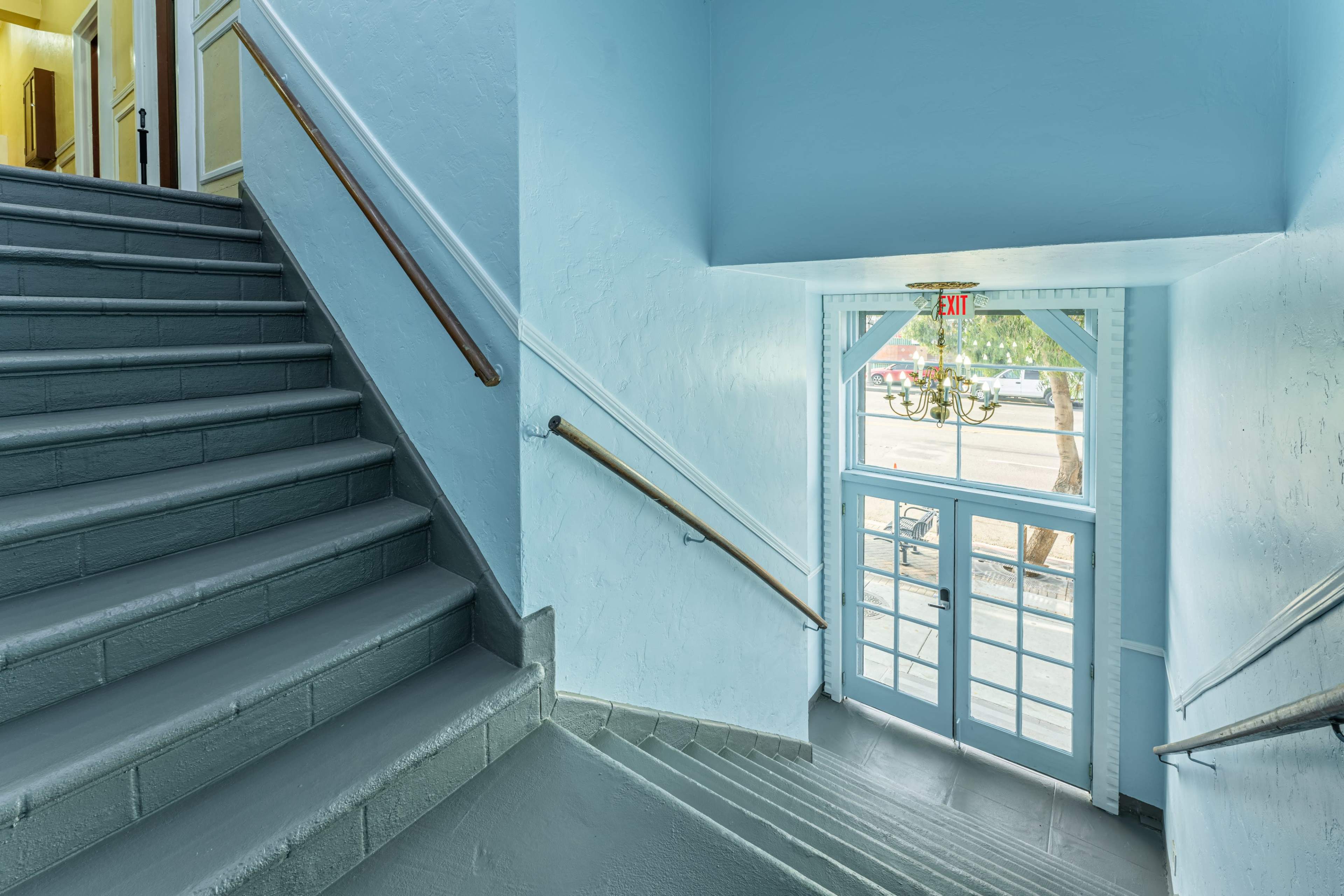 A light blue stairway leads to a double door entrance with windows, allowing natural light to illuminate the space.