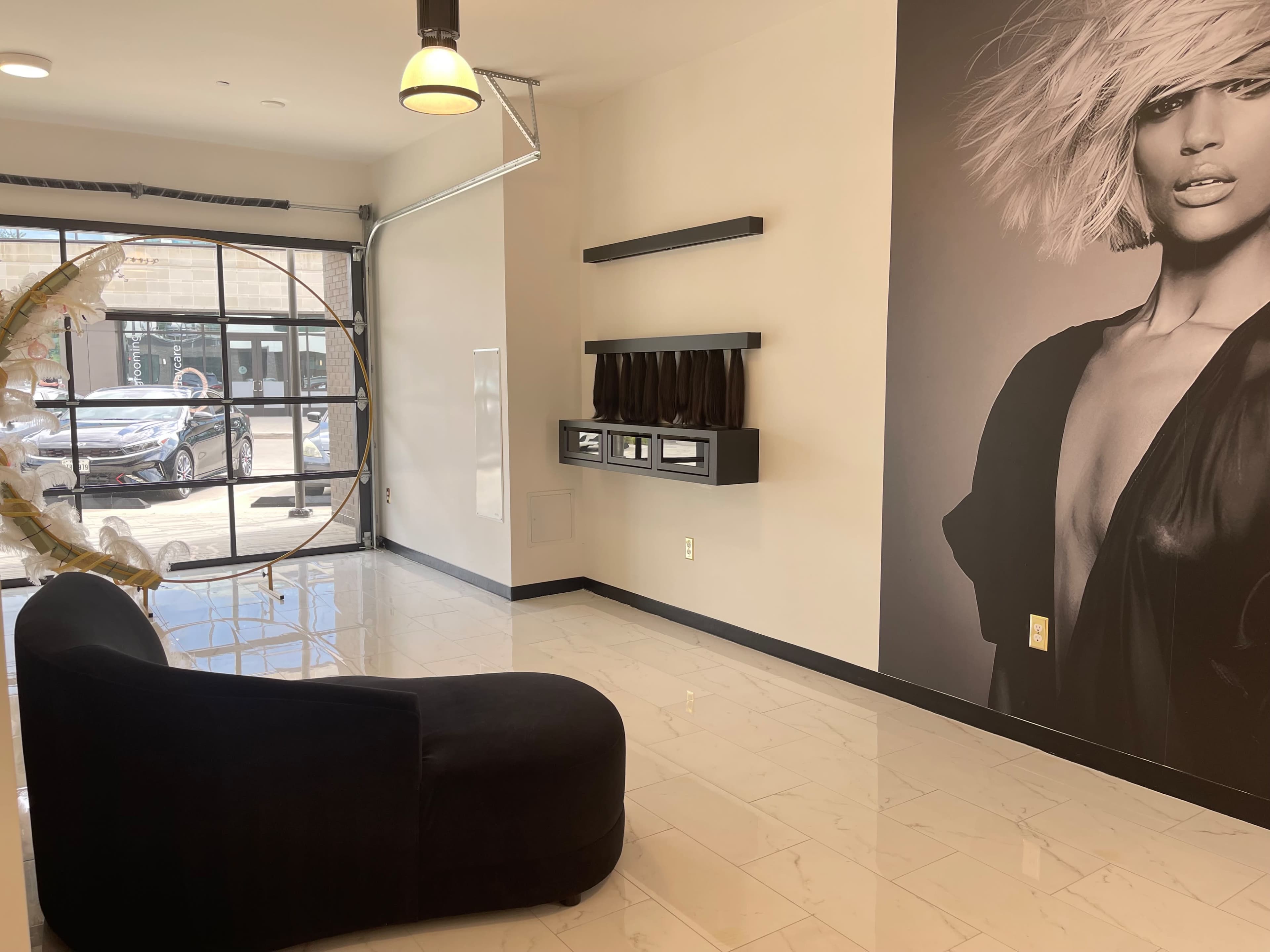 The image shows a modern interior space with a black curved couch, a wall featuring a large black-and-white portrait, and a large glass door leading outside.