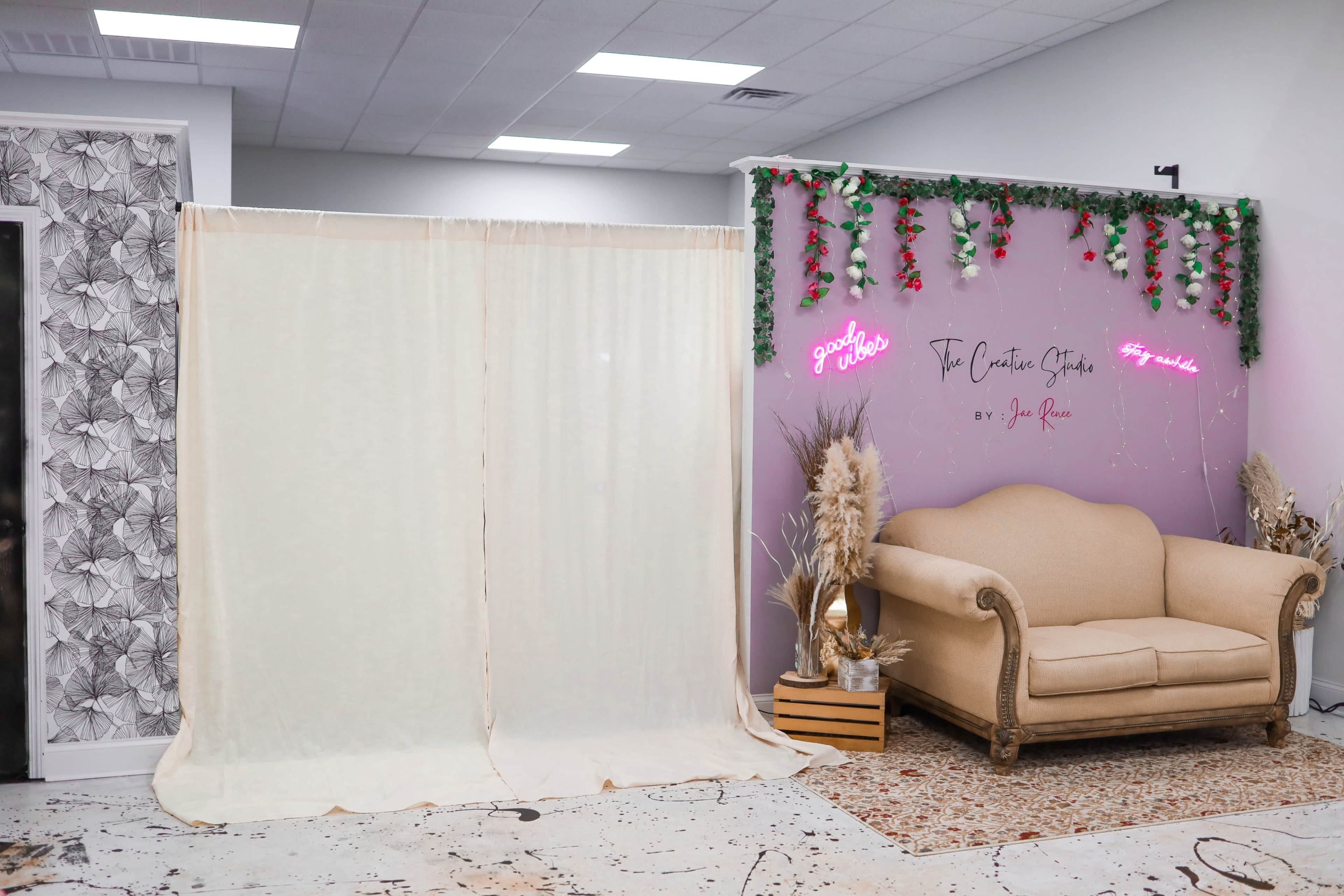 The scene features a spacious room with a draped curtain on one side and a decorative wall with a neon sign and a vintage sofa on the other.