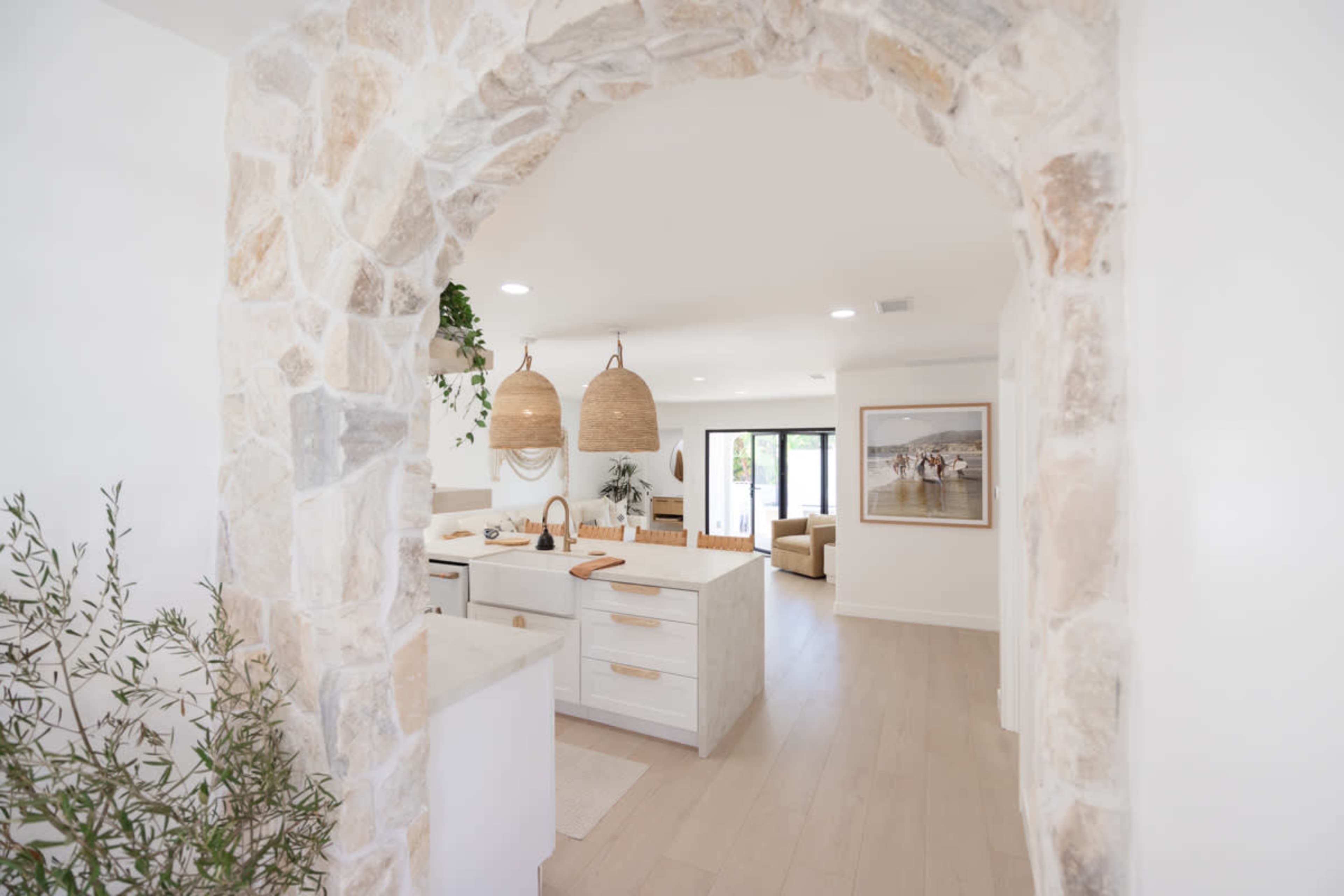 A view of a modern kitchen and living area framed by a stone archway.
