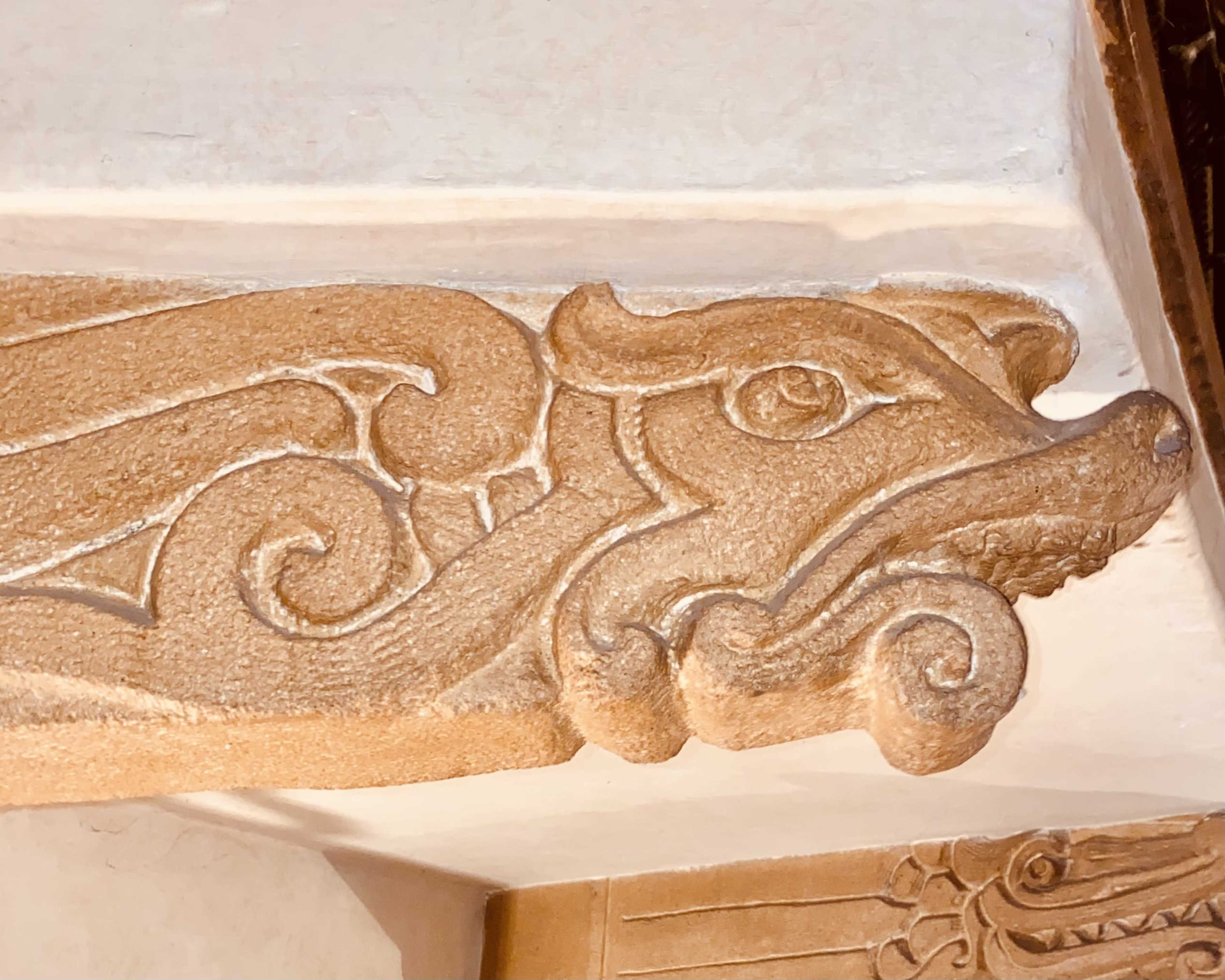 The image shows an intricately carved stone relief of a stylized dragon or serpent with swirling patterns.