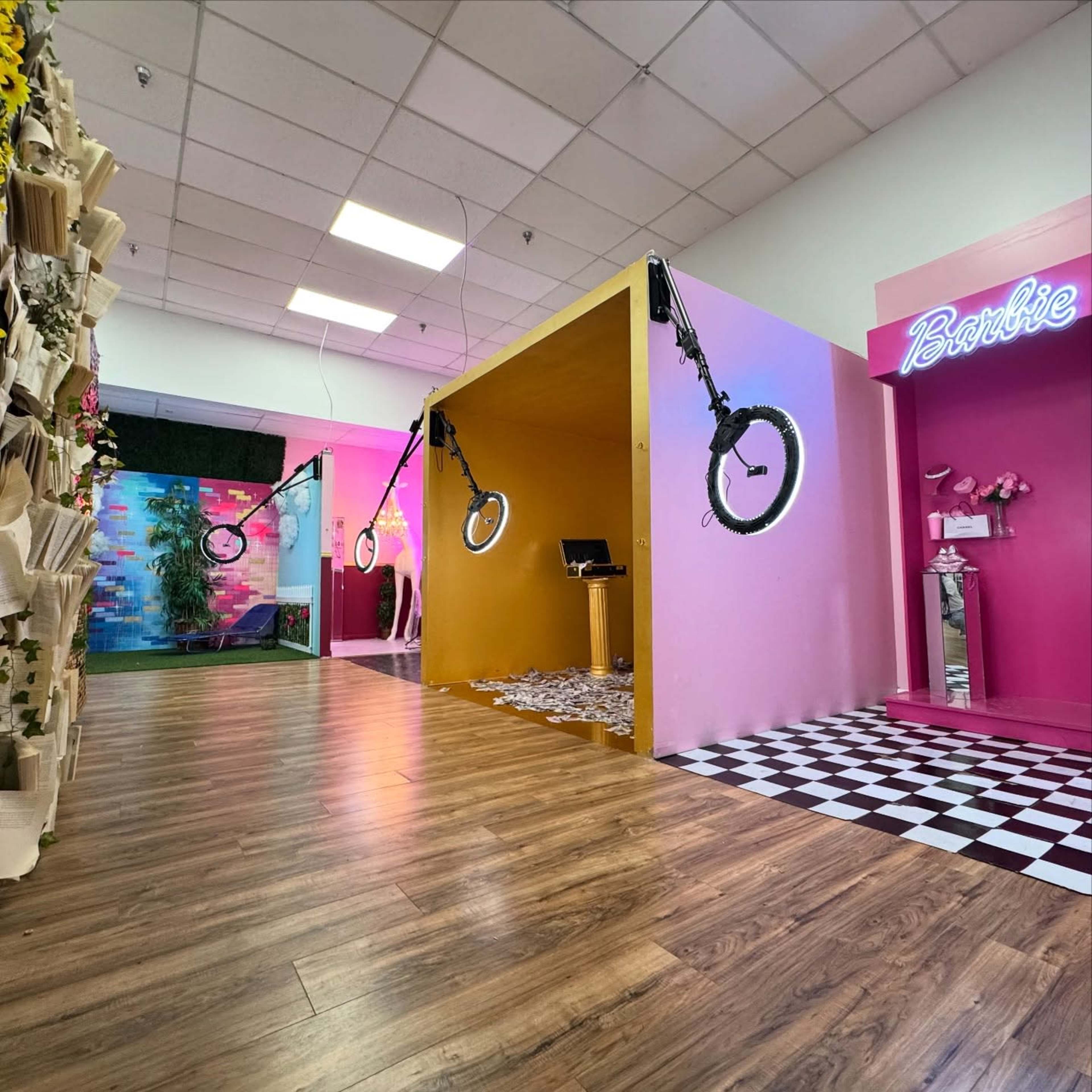 The image shows a brightly colored indoor space with distinct sections featuring pink and yellow walls, circular lighting fixtures, and a checkerboard floor.