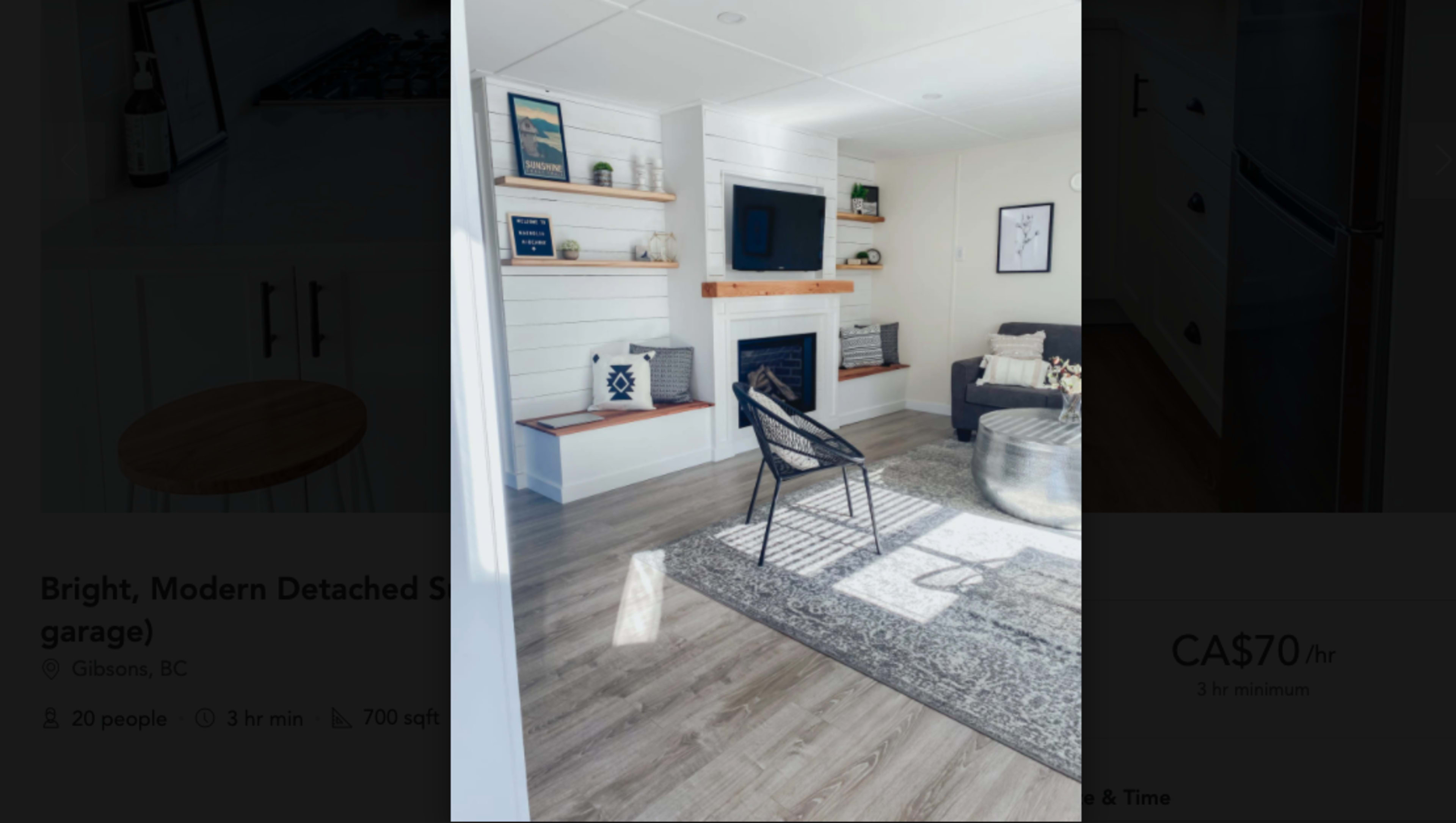 The image shows a modern room with a fireplace, wall shelves, a gray sofa, and a decorative rug on the floor.