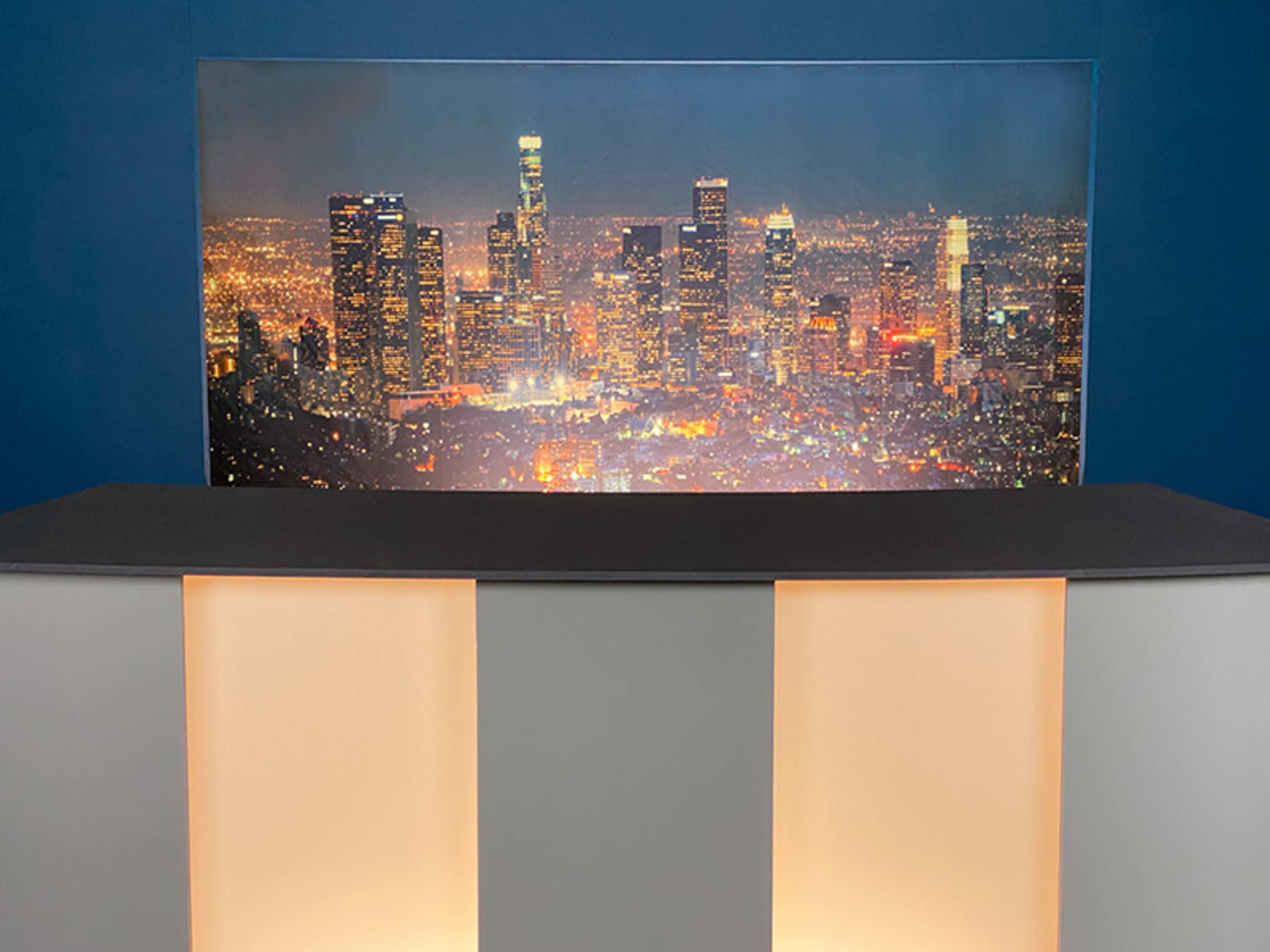 A reception desk in front of a large backdrop featuring a city skyline illuminated at night.