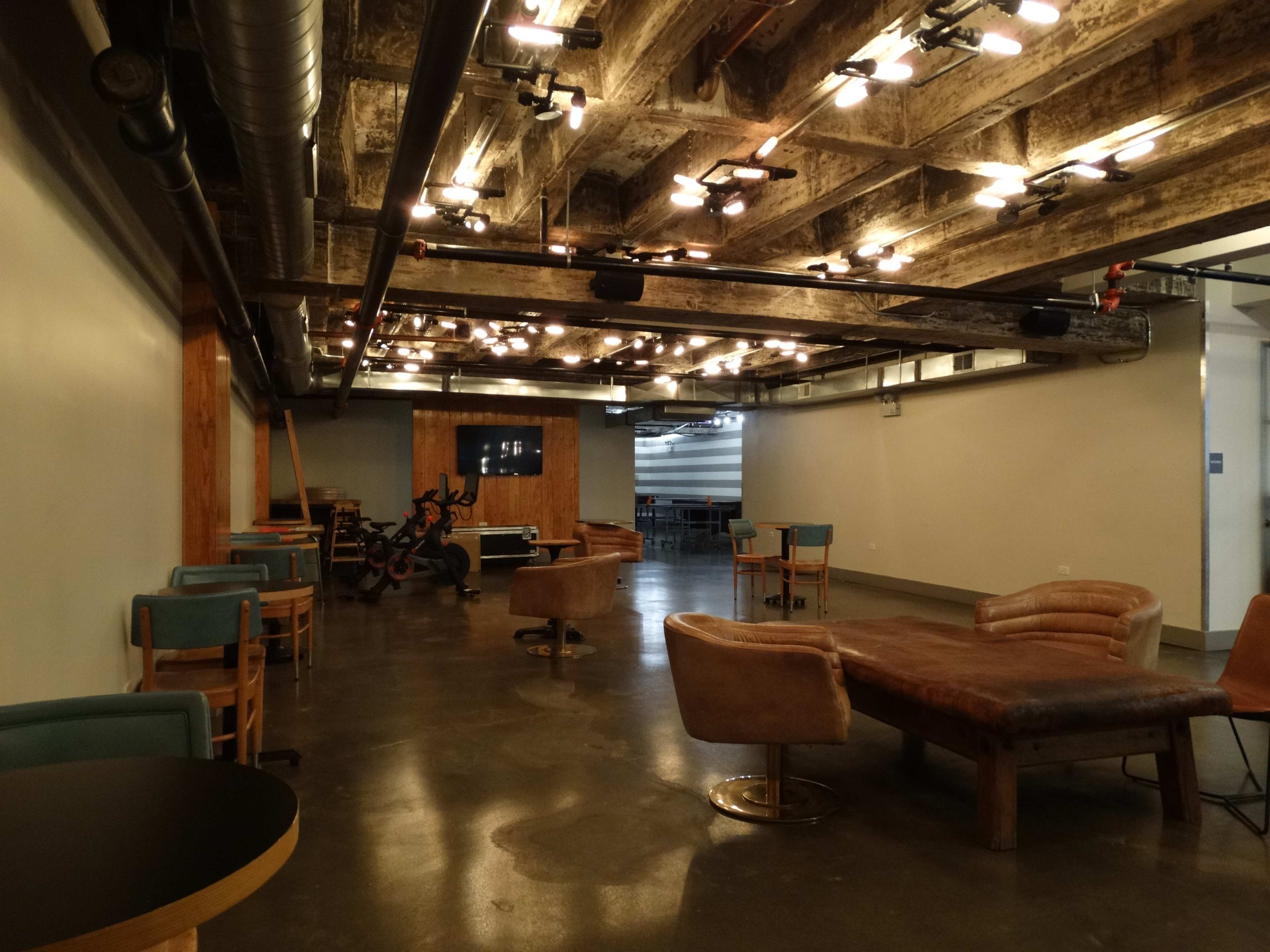 A spacious, modern lounge area with wooden beams, seating arrangements, a billiards table, and soft lighting.