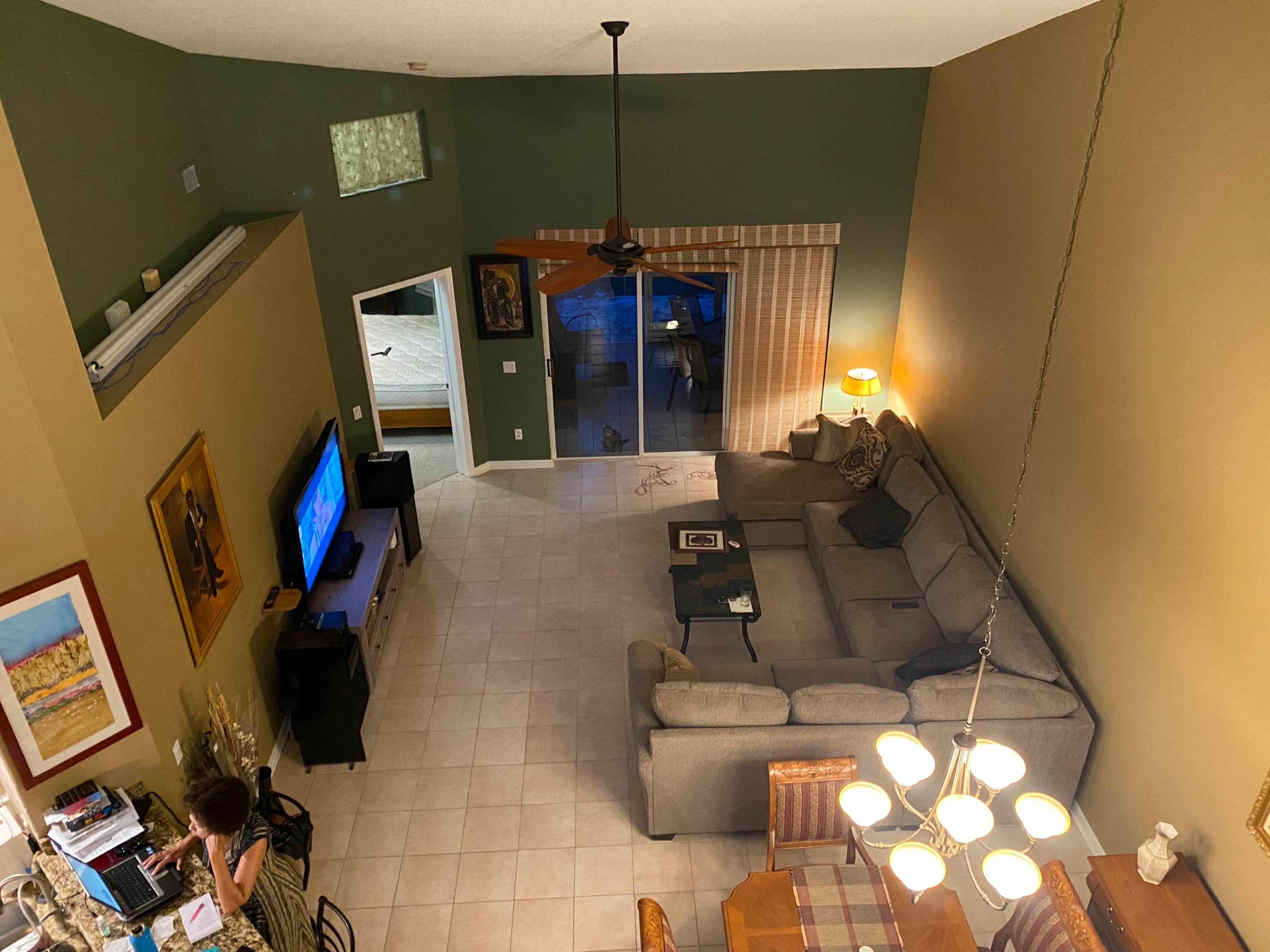 A spacious living area with a sectional sofa, a television, and a dining table, viewed from an elevated perspective.