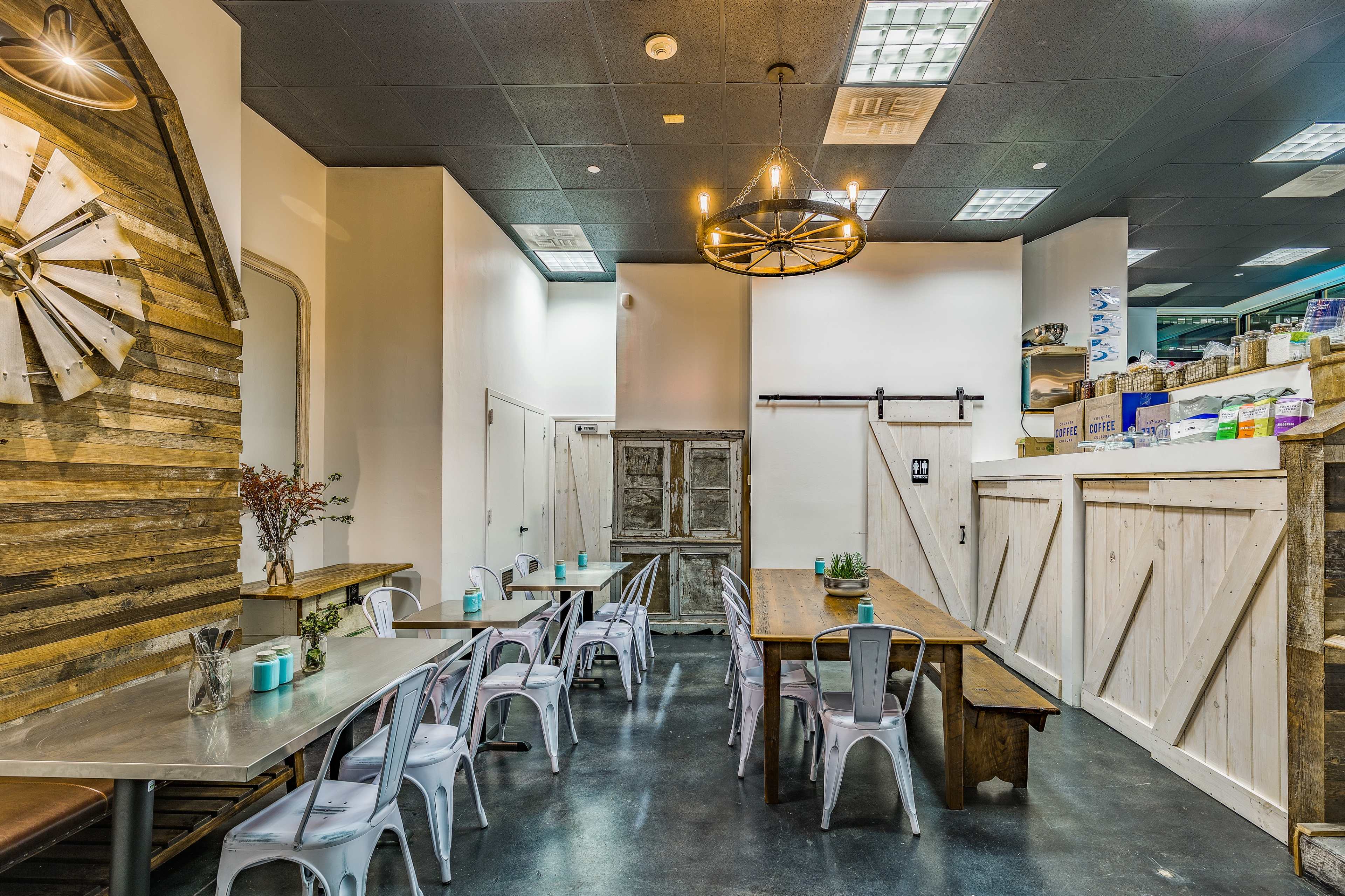 A modern restaurant interior featuring wooden accents, a mix of tables and chairs, and a simple layout.