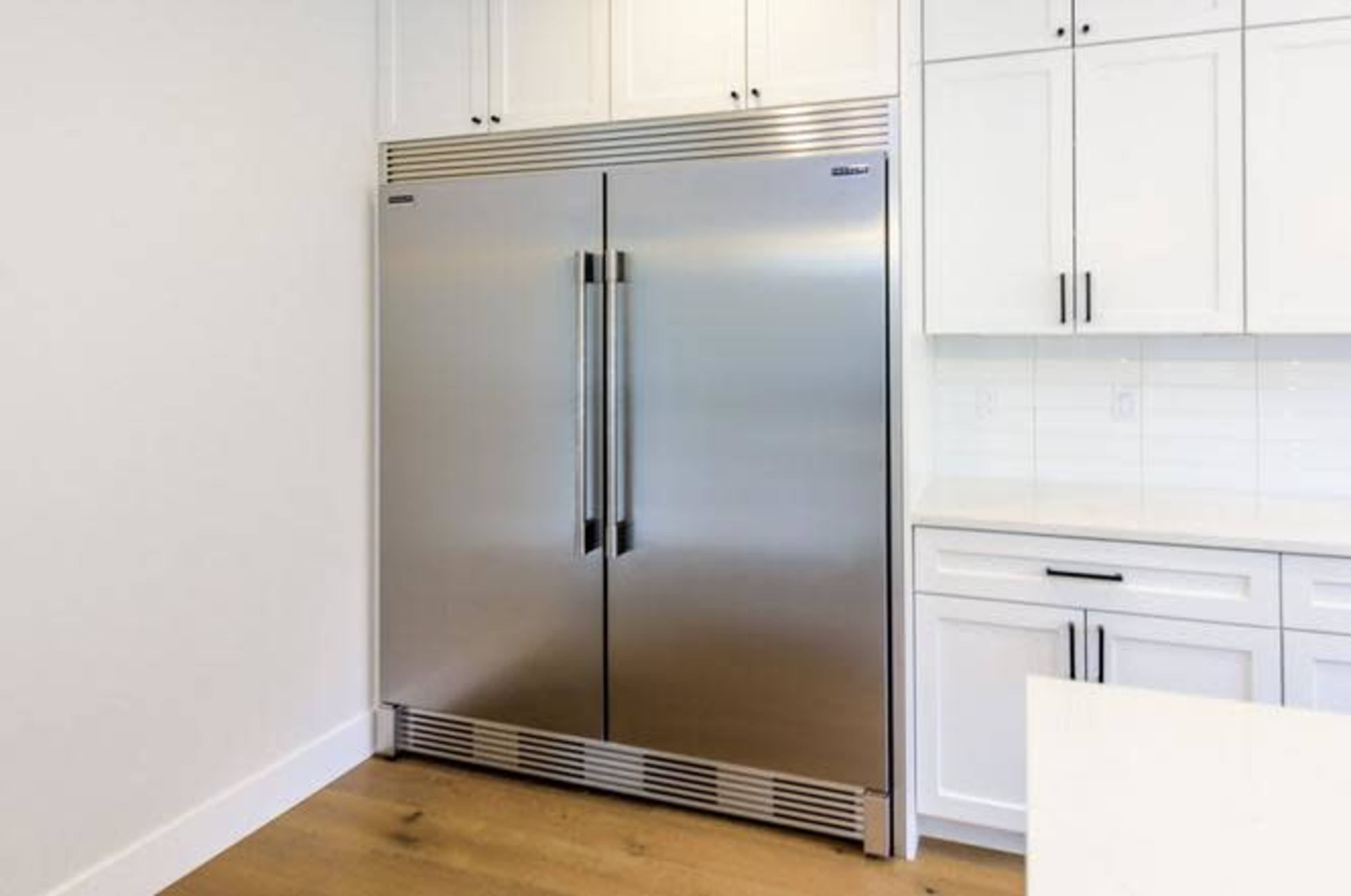 A large stainless steel refrigerator with double doors is installed in a modern kitchen.