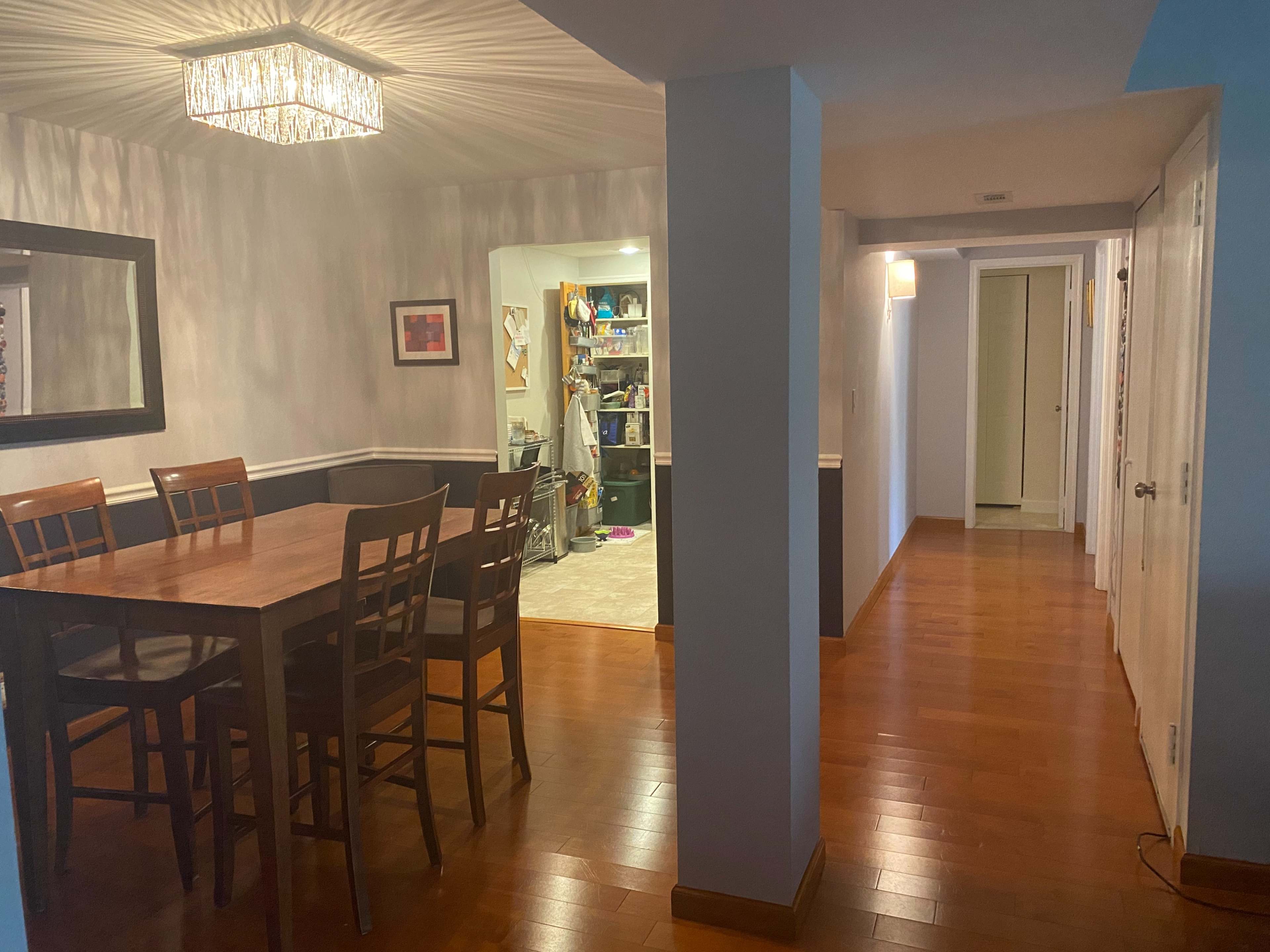 A dining area with a wooden table and chairs adjacent to a hallway leading to other rooms.