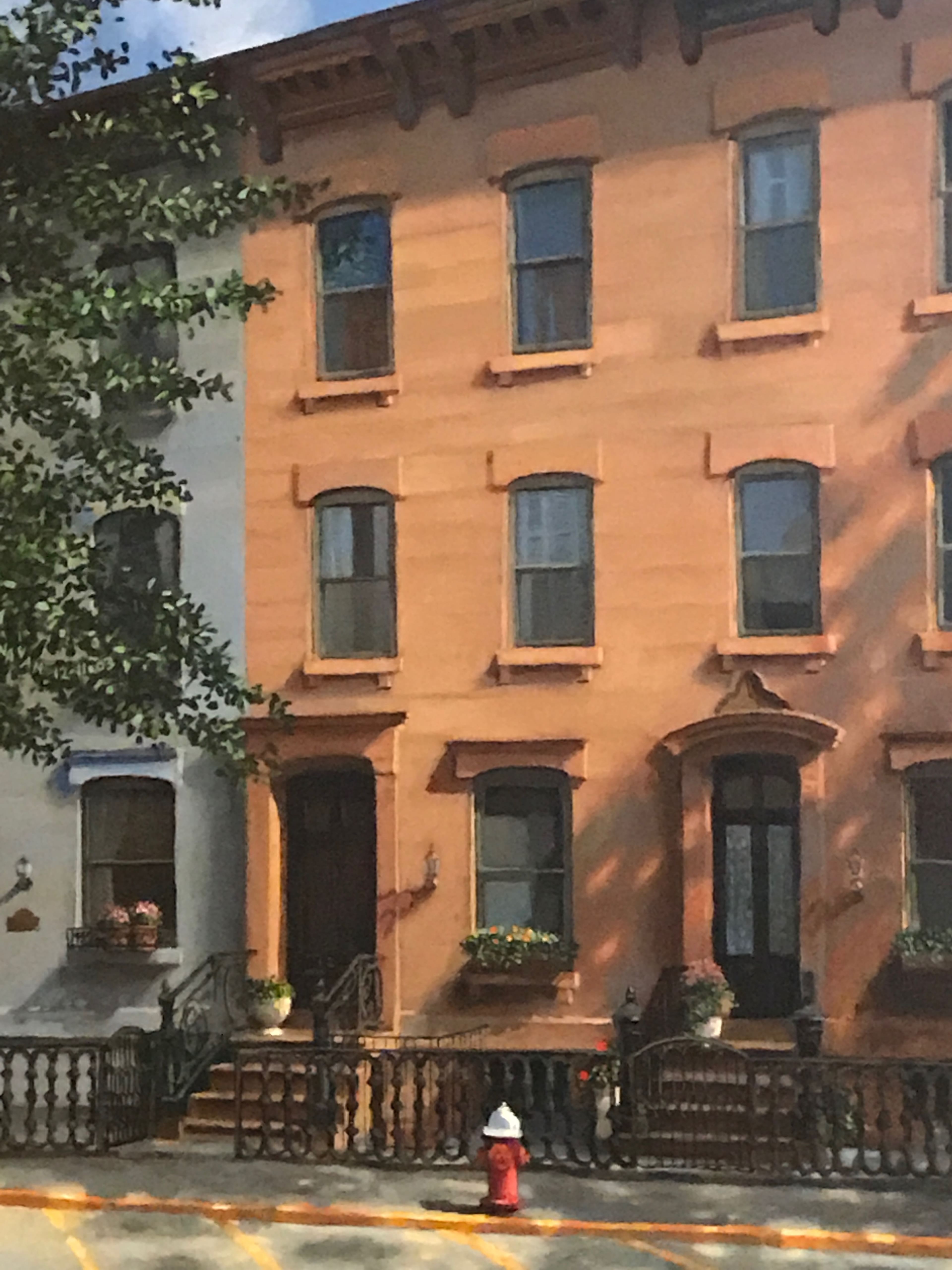 A residential building with a peach-colored facade, featuring multiple windows and a small front garden, adjacent to a sidewalk and a fire hydrant.