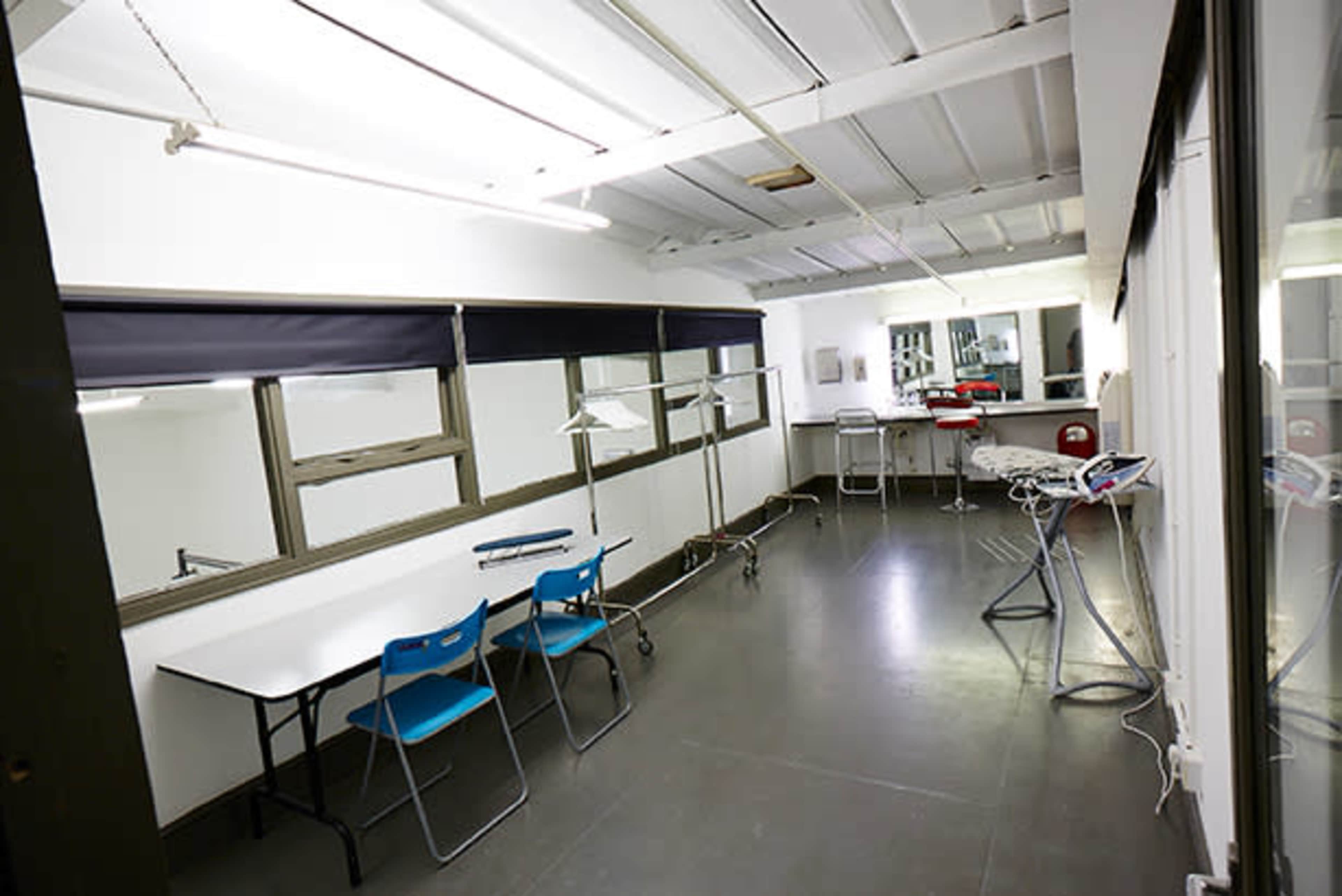 A spacious, well-lit room with a long table, blue chairs, and various equipment along the walls.