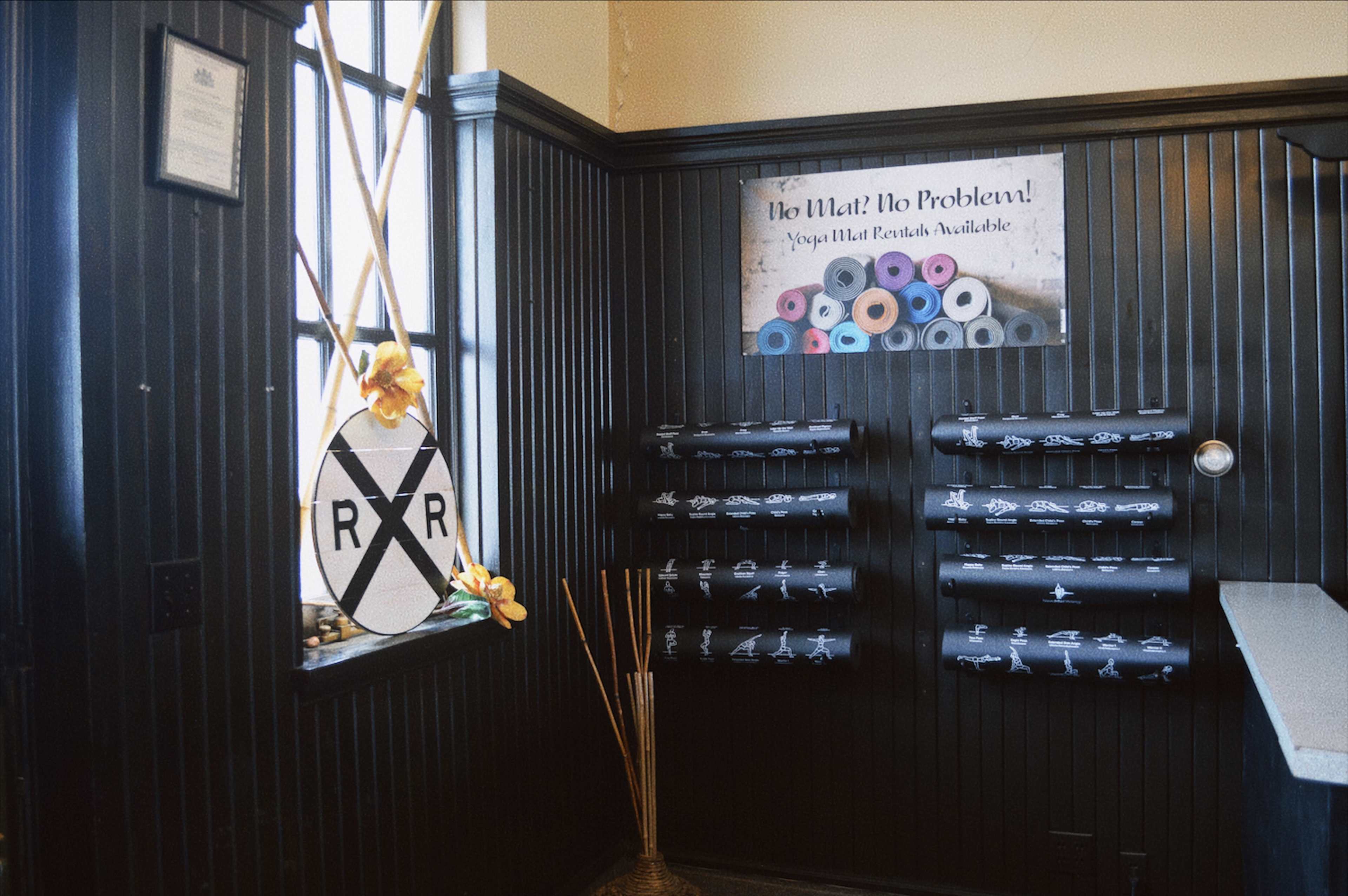 A corner of a room with black wooden paneling, featuring a window, a decorative sign, and rolls of gift wrap displayed on a wall.