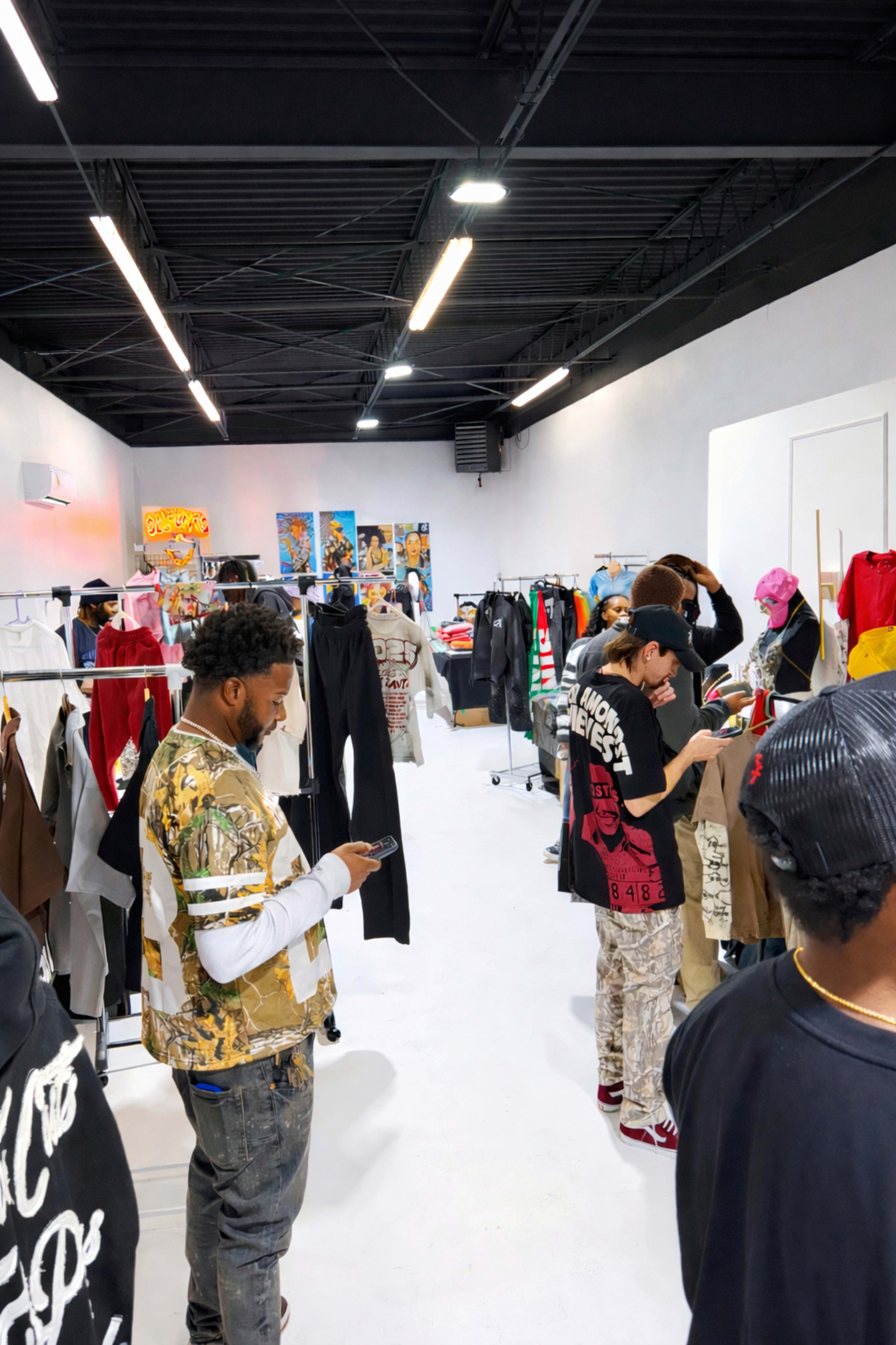 The image shows a clothing store filled with racks of apparel and several customers browsing through the items.