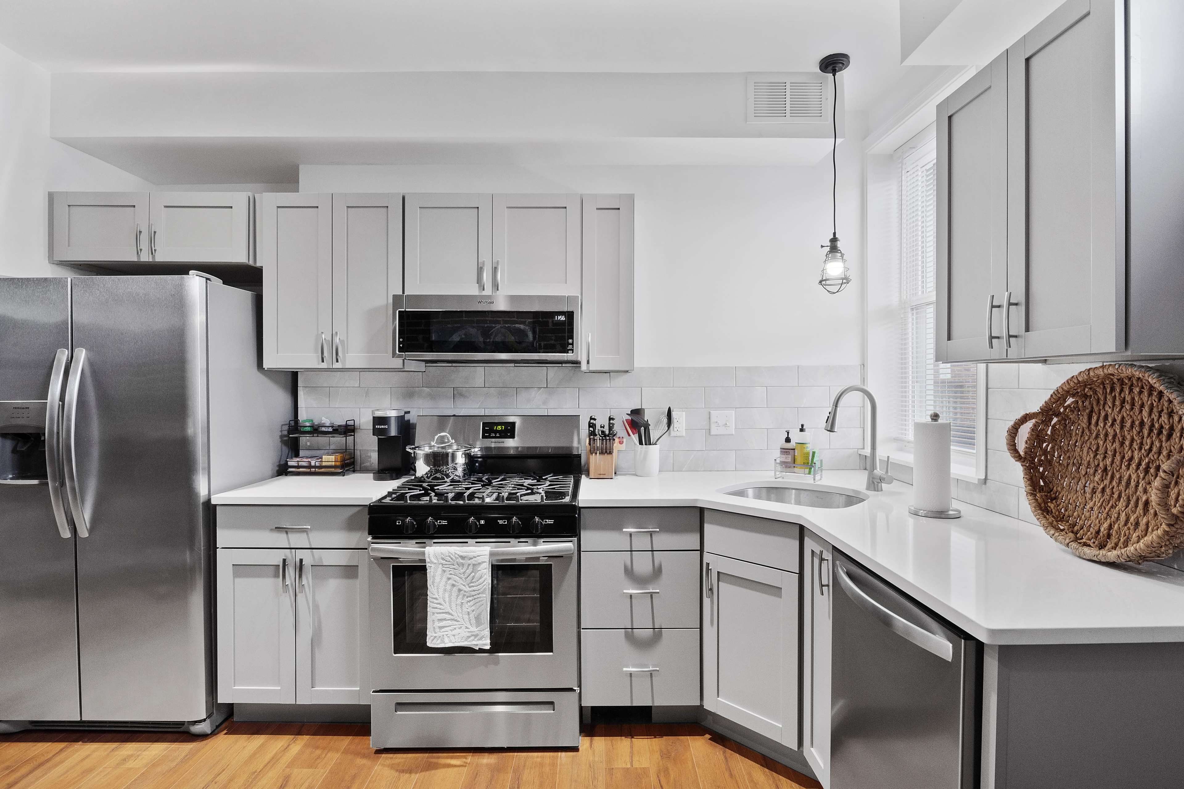 The kitchen features gray cabinets, stainless steel appliances, and a white countertop with a sink.