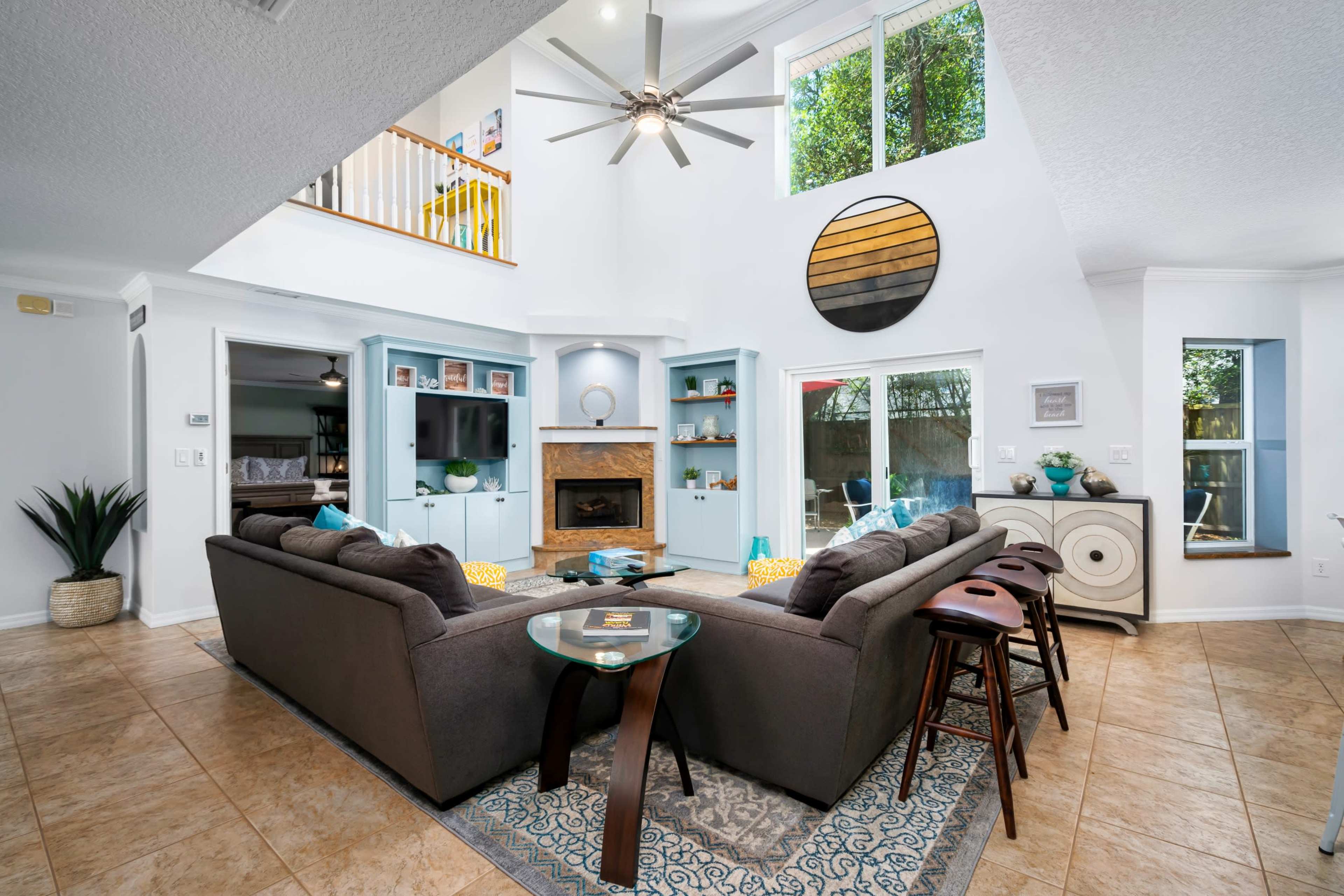 A spacious living room with a modern design, featuring a large sectional sofa, a central coffee table, and built-in shelves around a fireplace.