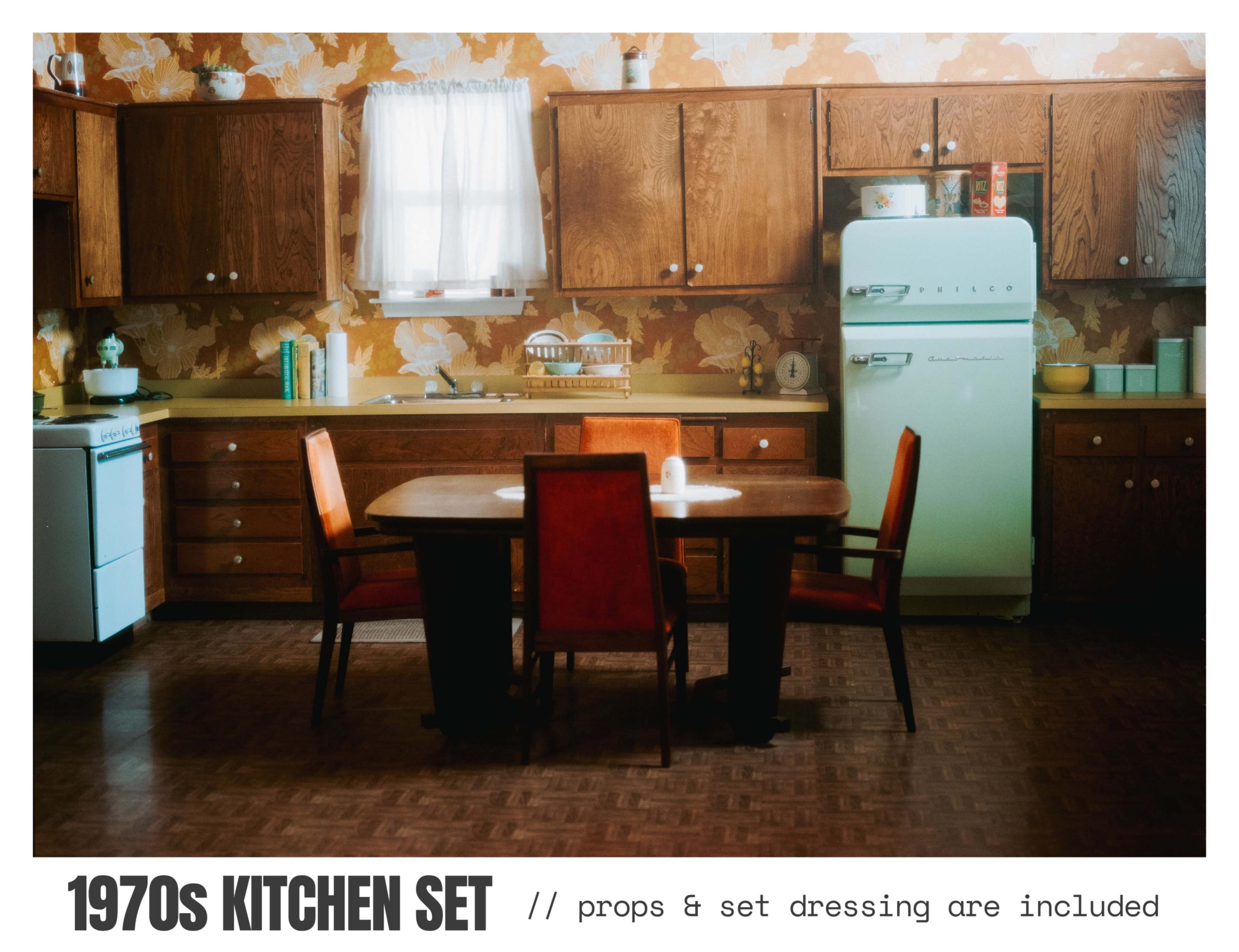The image shows a 1970s-themed kitchen set with wooden cabinets, a retro refrigerator, and a dining table surrounded by orange chairs.