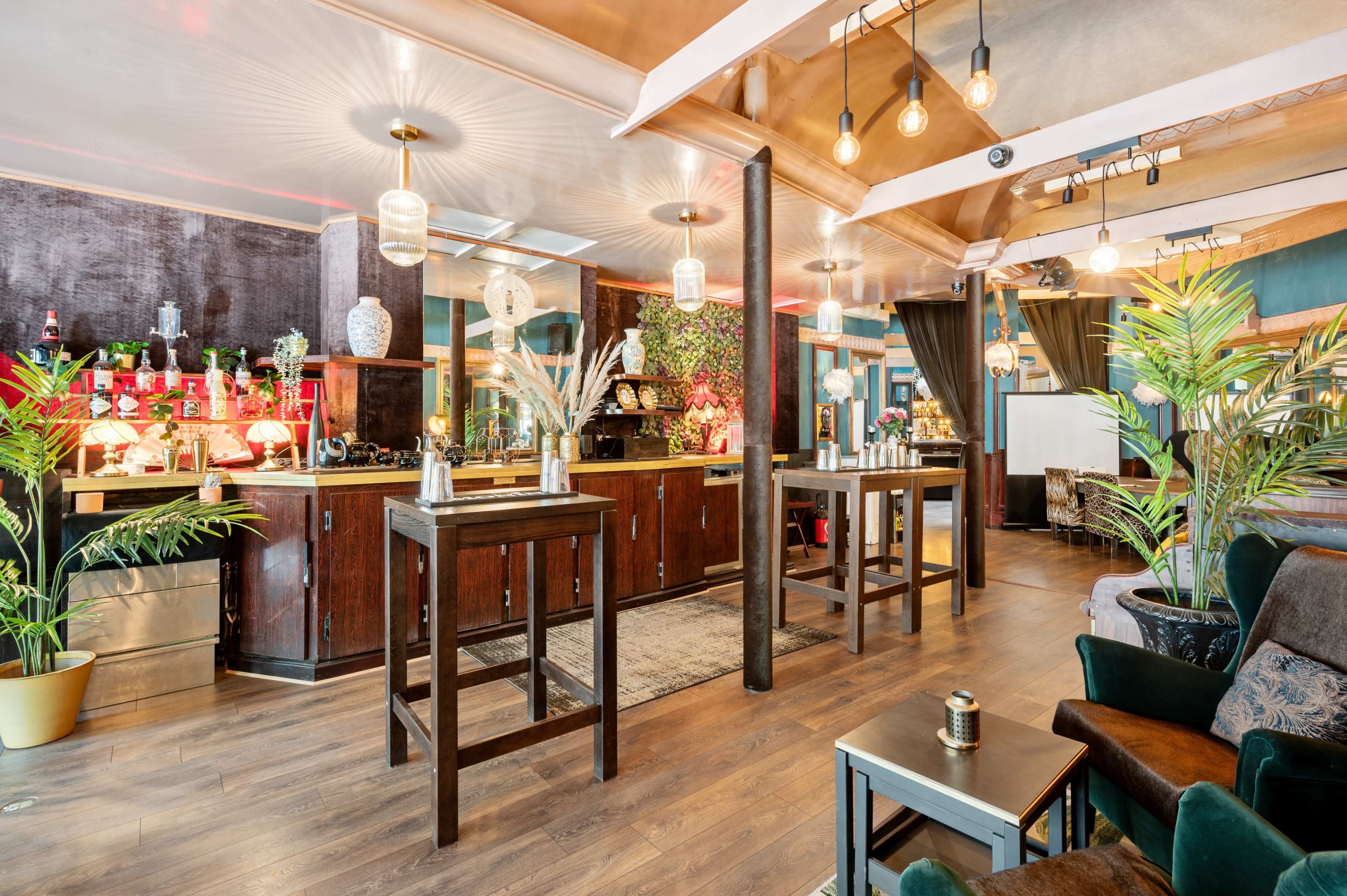A stylish bar area with wooden counters, plants, and a variety of bottles displayed on shelves in a modern interior design.