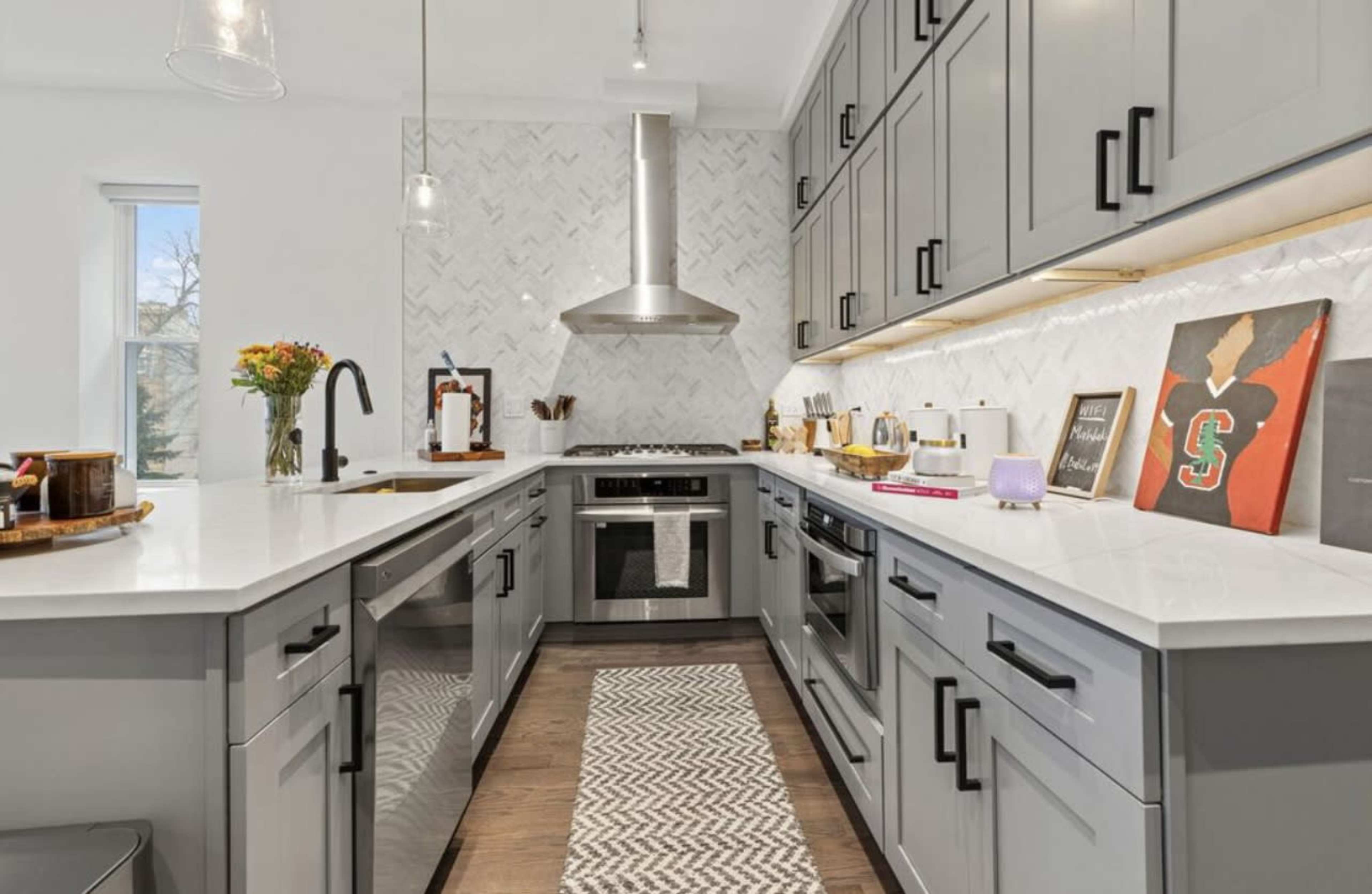 The kitchen features gray cabinetry, stainless steel appliances, and a white countertop with a patterned backsplash.