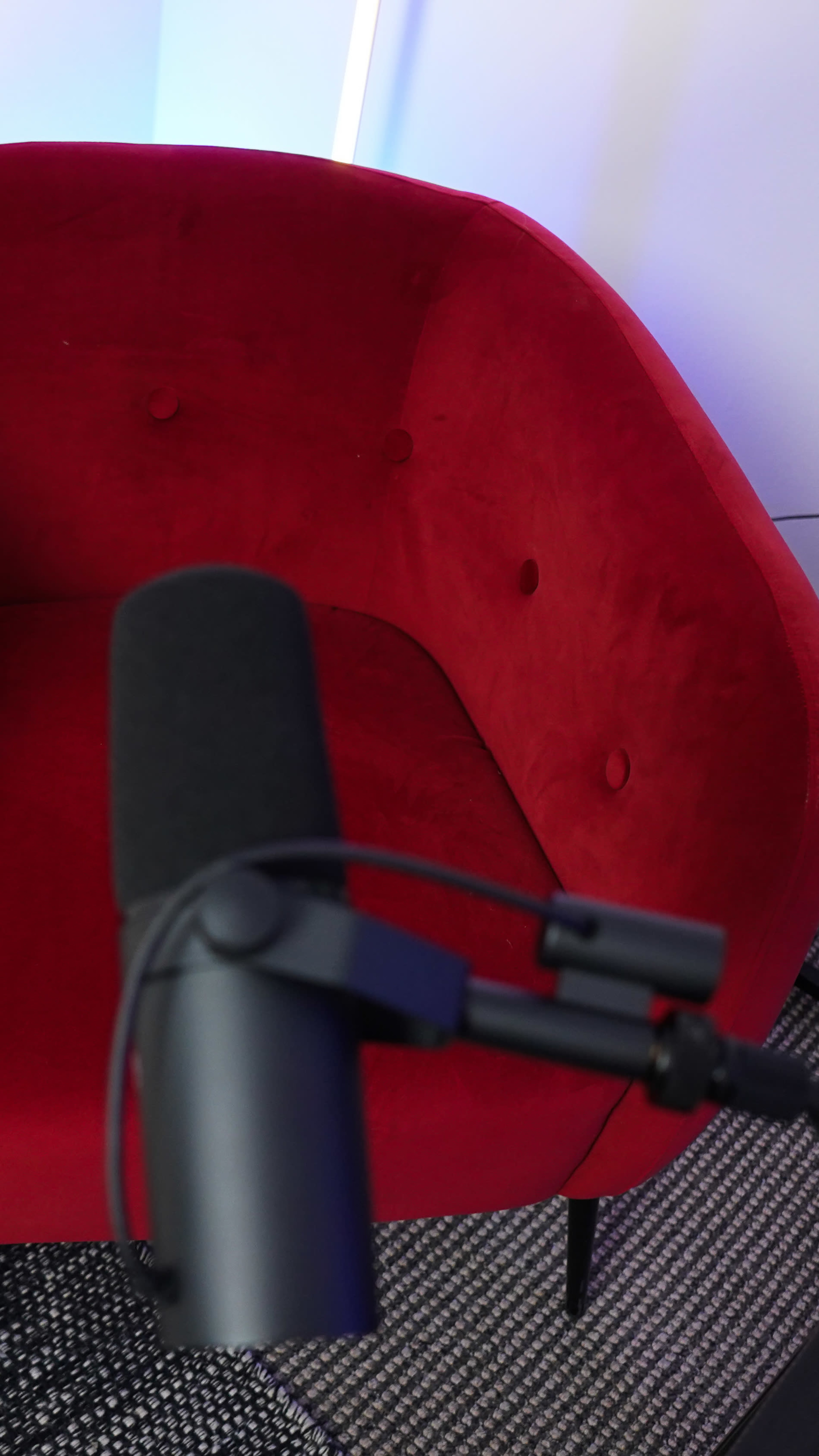 The image shows a red, upholstered chair with buttons, partially obscured by a microphone in the foreground.