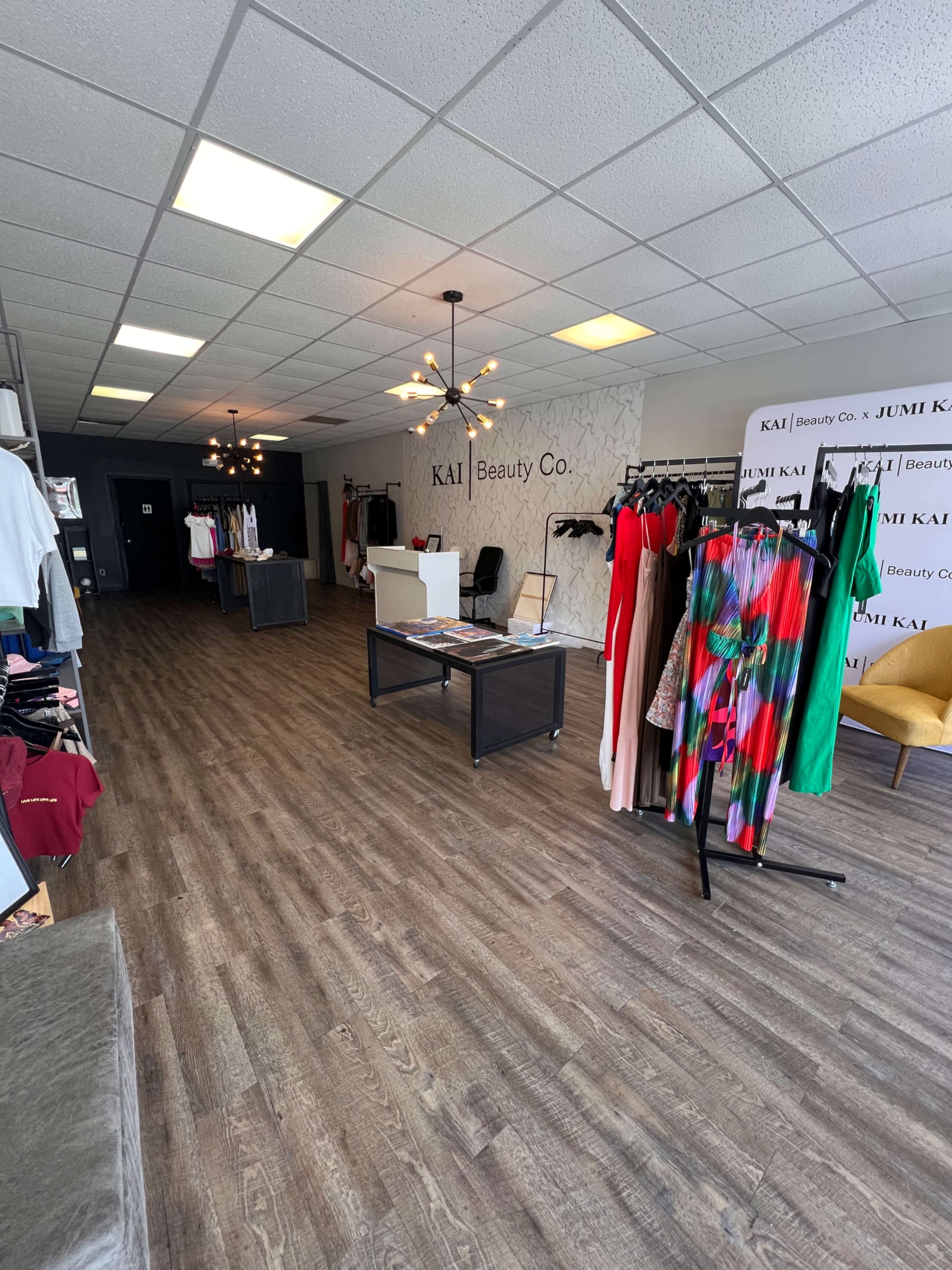 The image shows the interior of a beauty shop with clothing displays, a reception area, and wooden flooring.