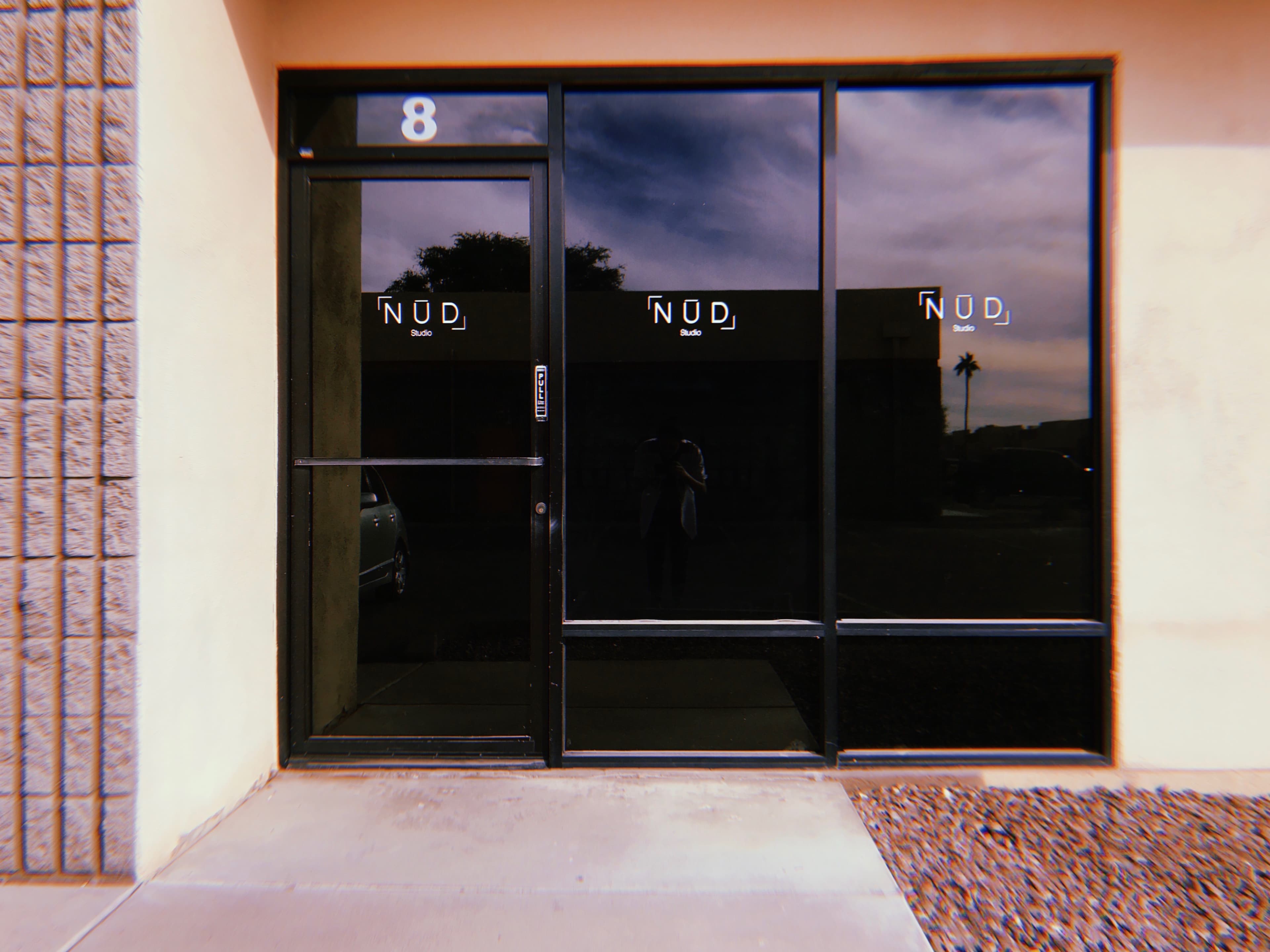 The entrance of a business with large glass windows displaying the name "NOD" and an adjacent door under the number 8.
