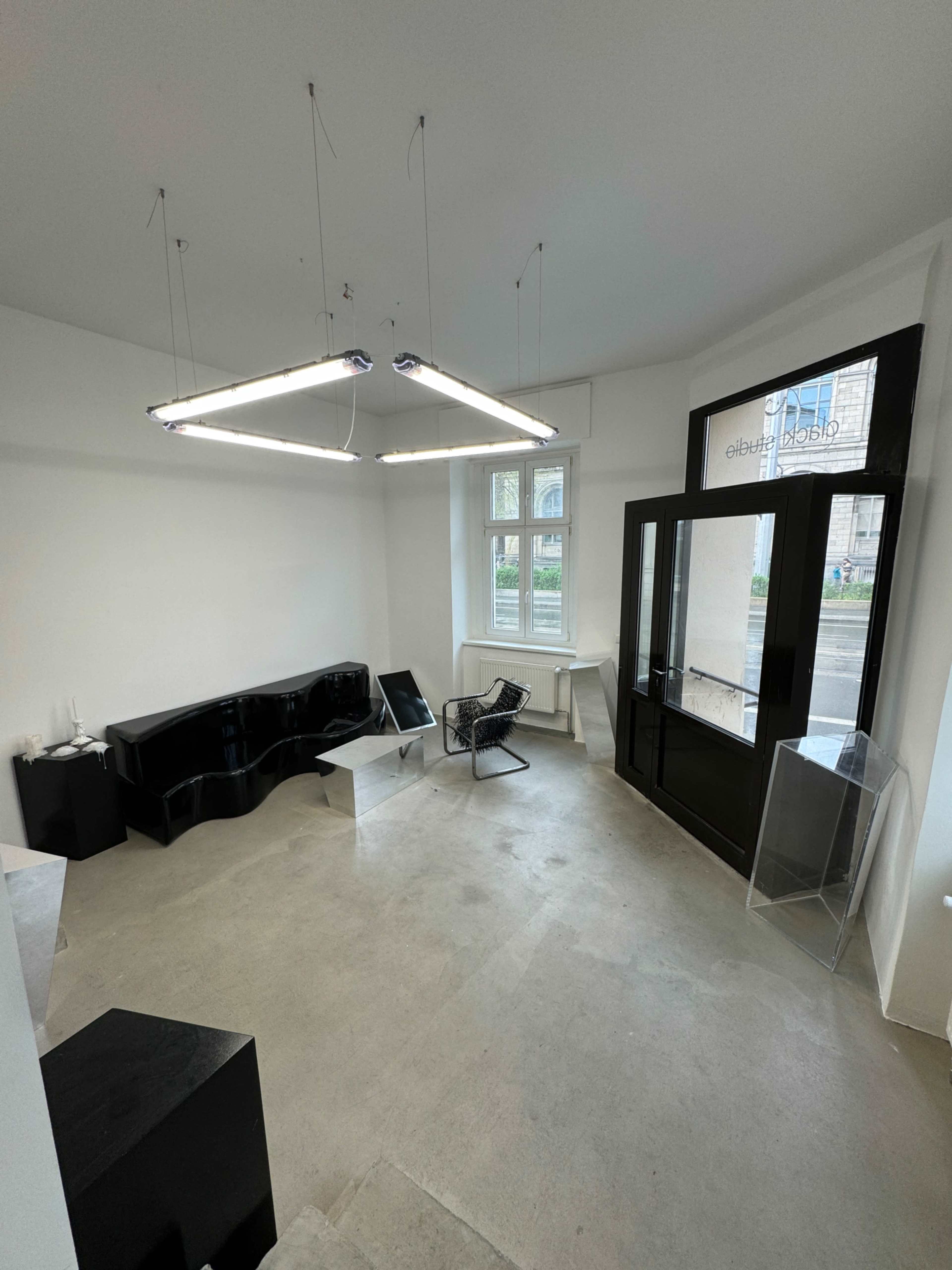 The interior of a minimalist gallery features sleek furniture and large windows allowing natural light to illuminate the space.