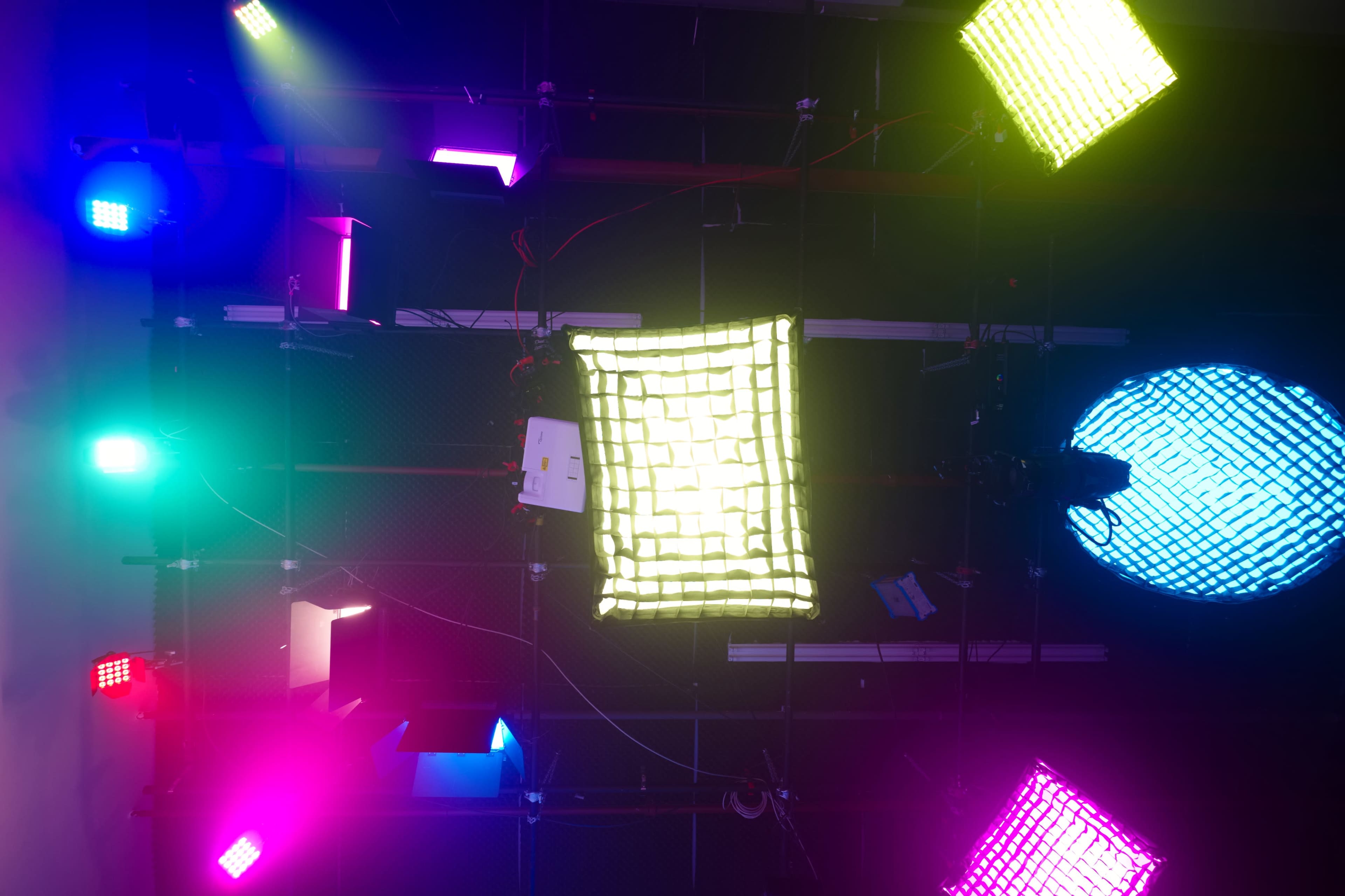 The image shows a grid of various colored stage lights arranged on a ceiling above a performance area.