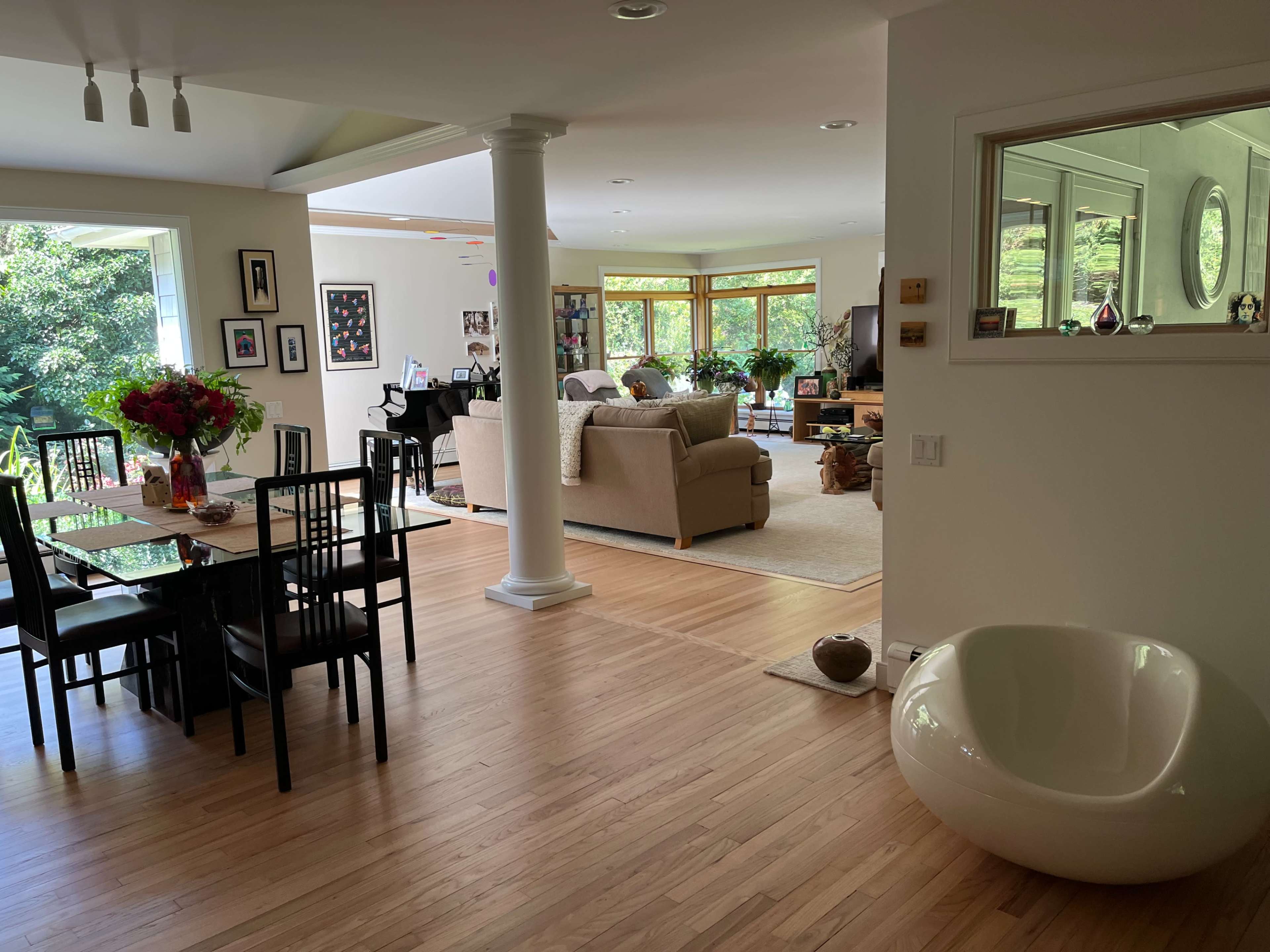An open-concept living space with a dining area, a living room, and large windows that allow natural light to fill the room.