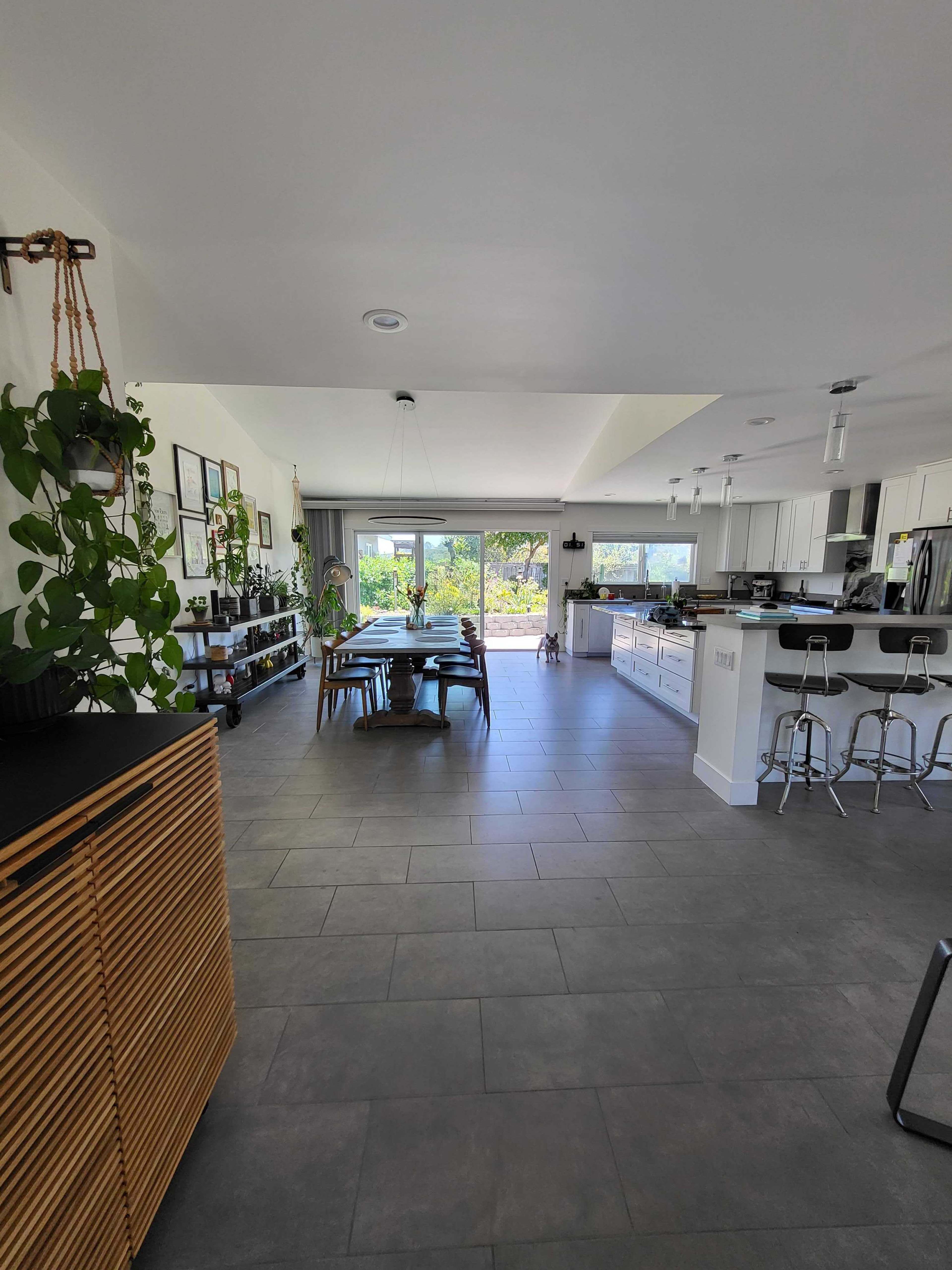 A modern kitchen and dining area with a view of a garden through large sliding glass doors.