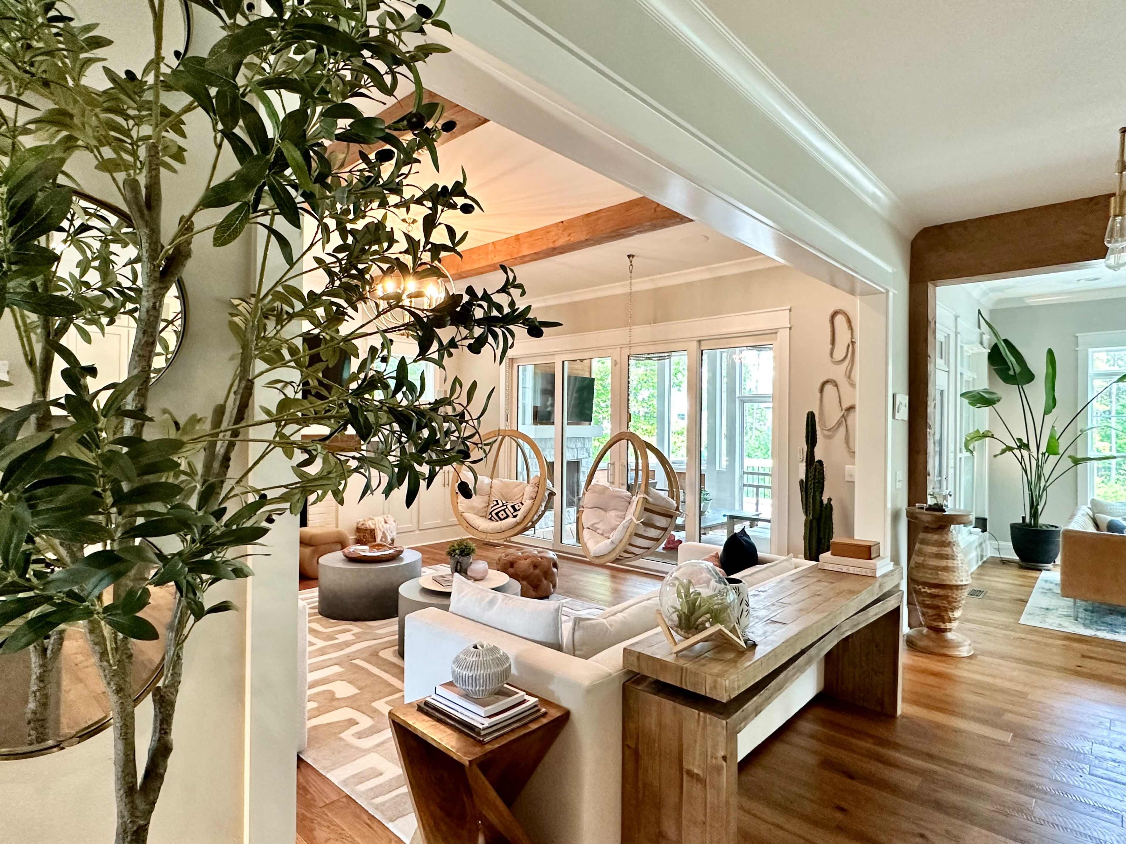 A bright, open living space featuring a sectional sofa, wooden accents, and two large hanging chairs framed by a decorative archway.