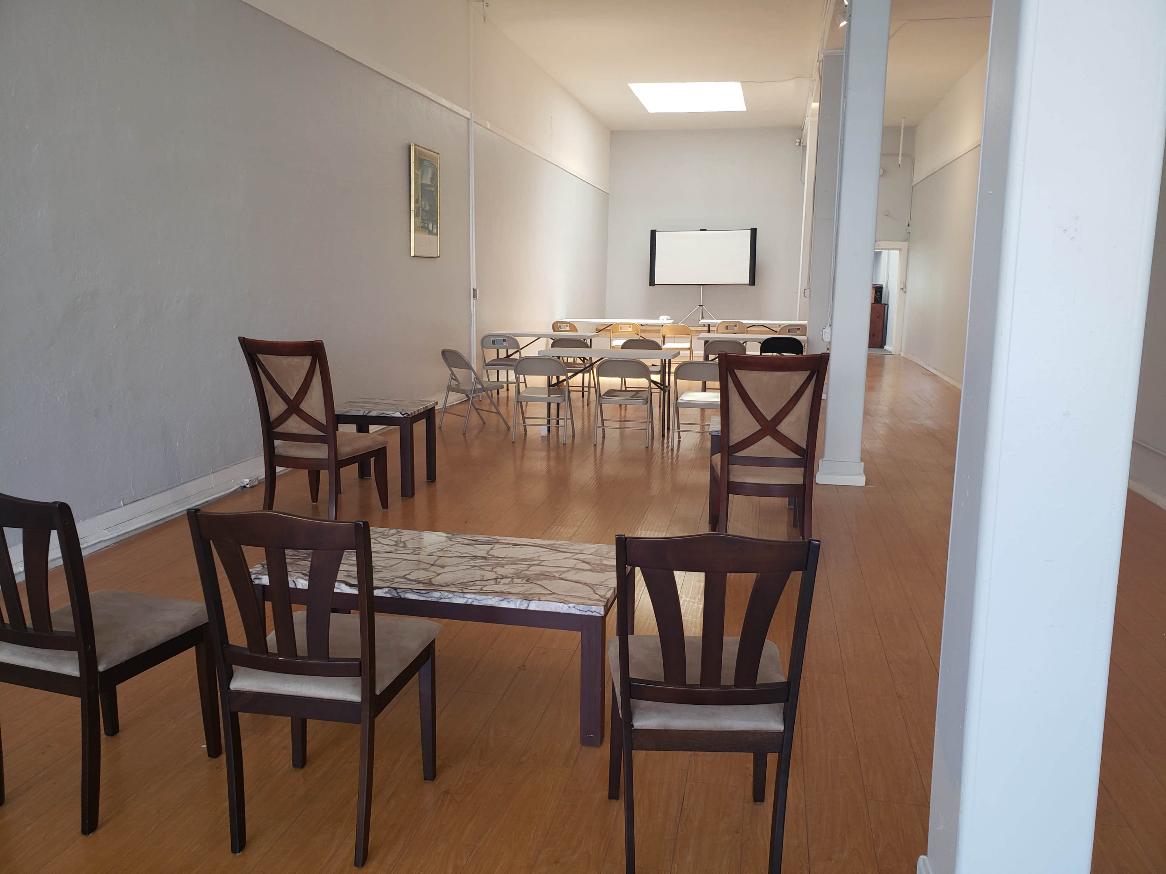 A spacious, empty room with a table set up for meetings, surrounded by several chairs arranged in a semi-circle.