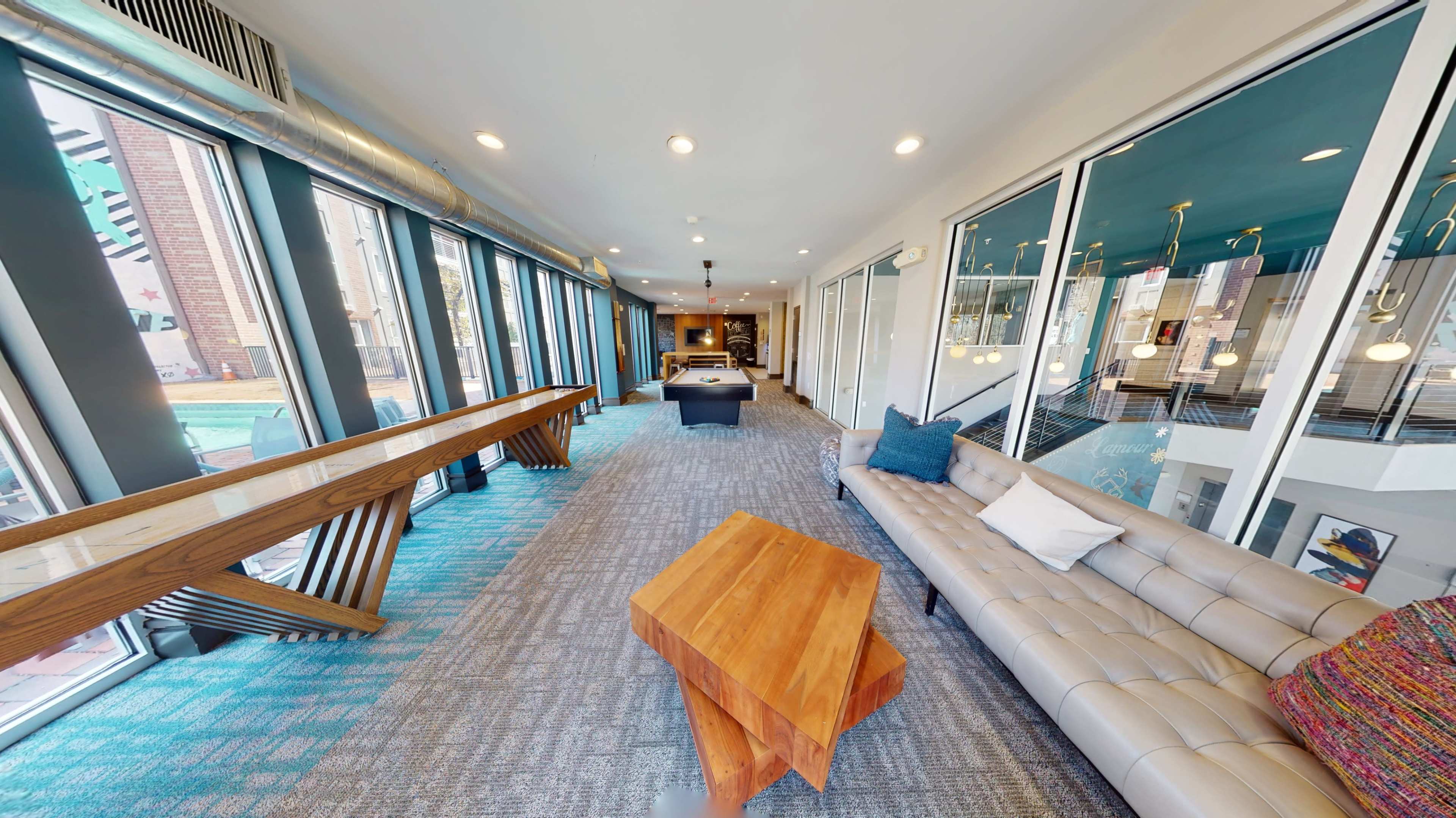 A modern lounge area with a stylish sofa, a wooden coffee table, and large windows overlooking an outdoor space.