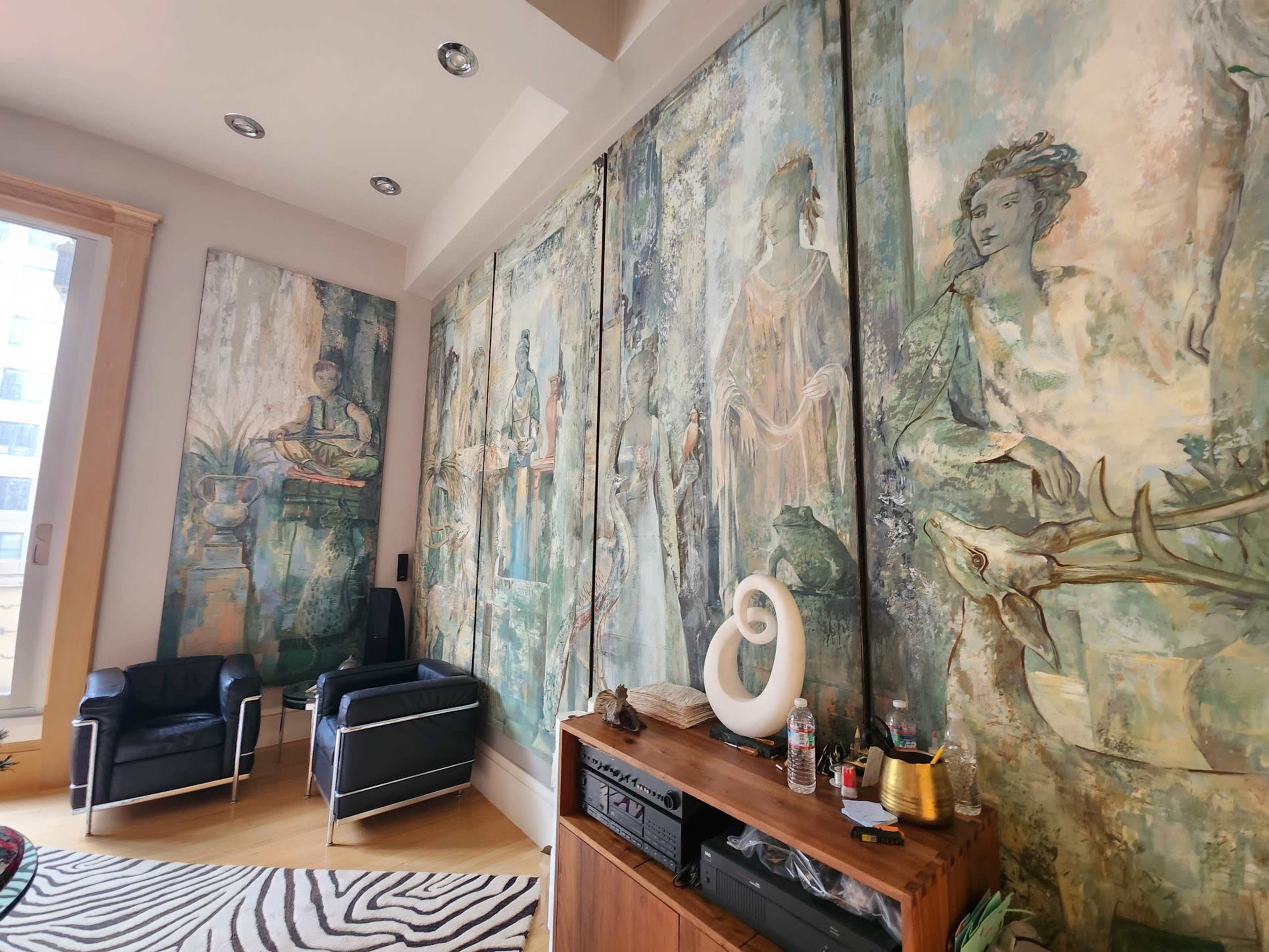 A room with large, artistic wall panels featuring figures and nature themes, two black chairs, and a wooden cabinet with various items on top.