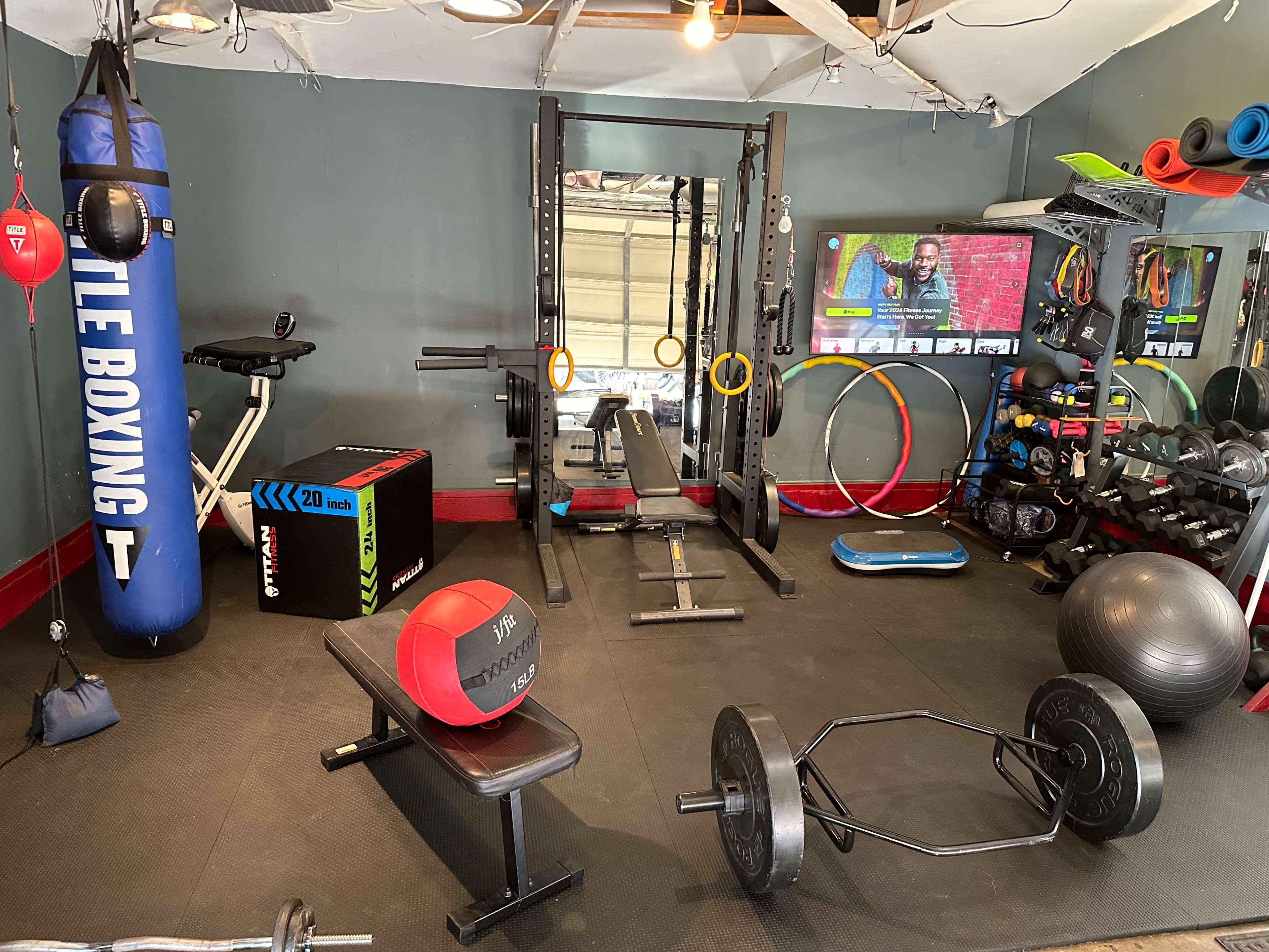 A home gym equipped with various exercise equipment, including weights, a boxing bag, a bench, and fitness accessories.