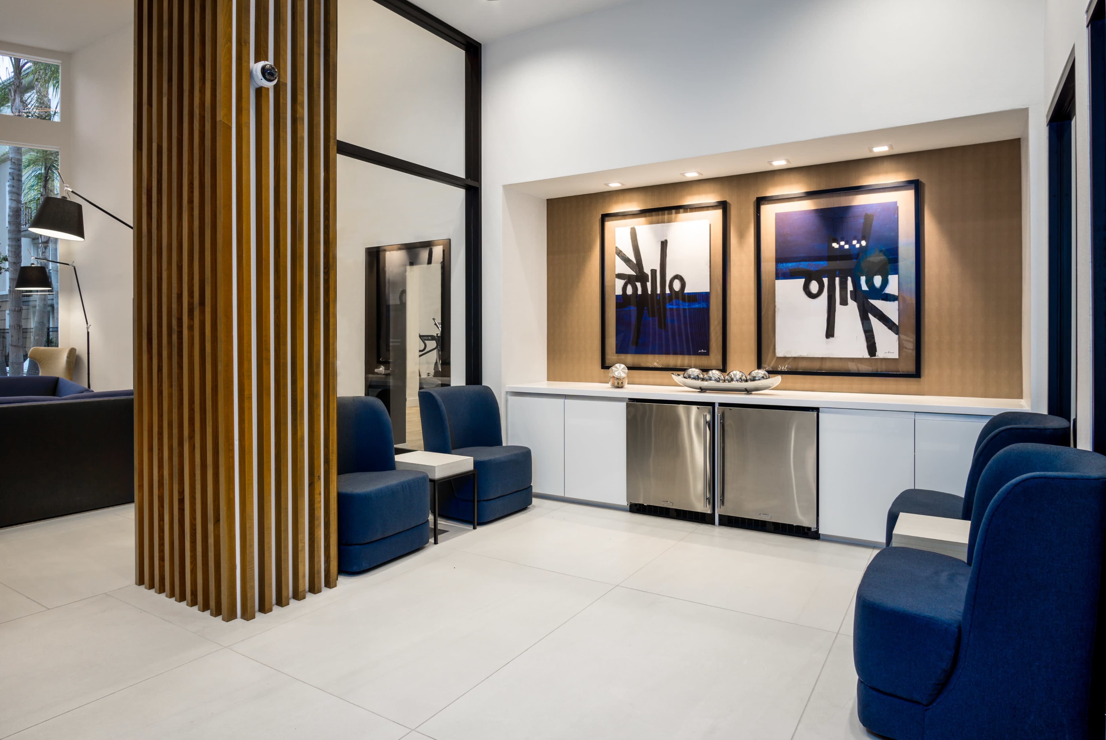 A modern interior space features blue seating, abstract artwork, and a sleek countertop with metallic finishes.