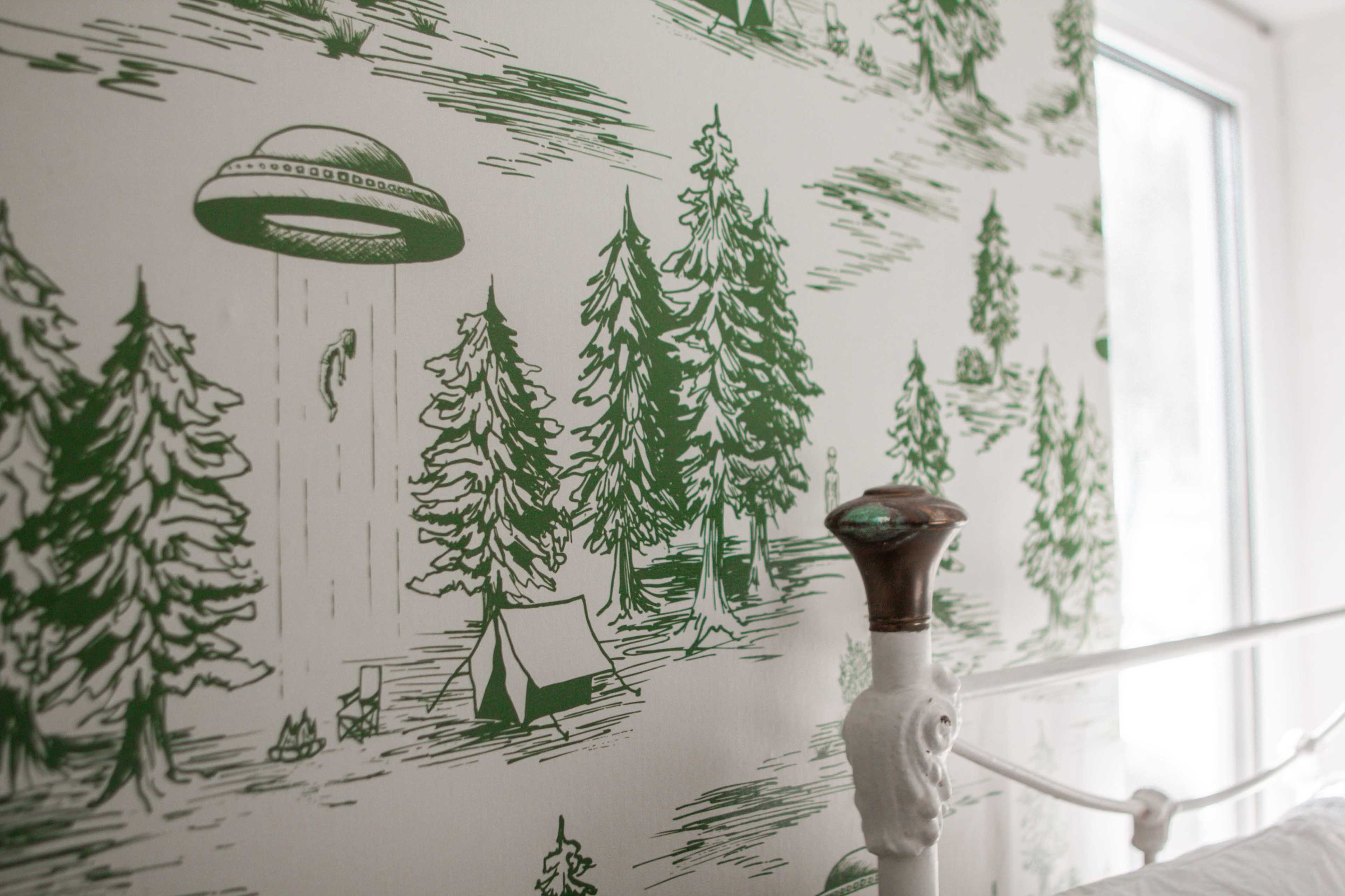 A patterned wallpaper depicting a forest scene with a flying saucer above trees and a campsite.