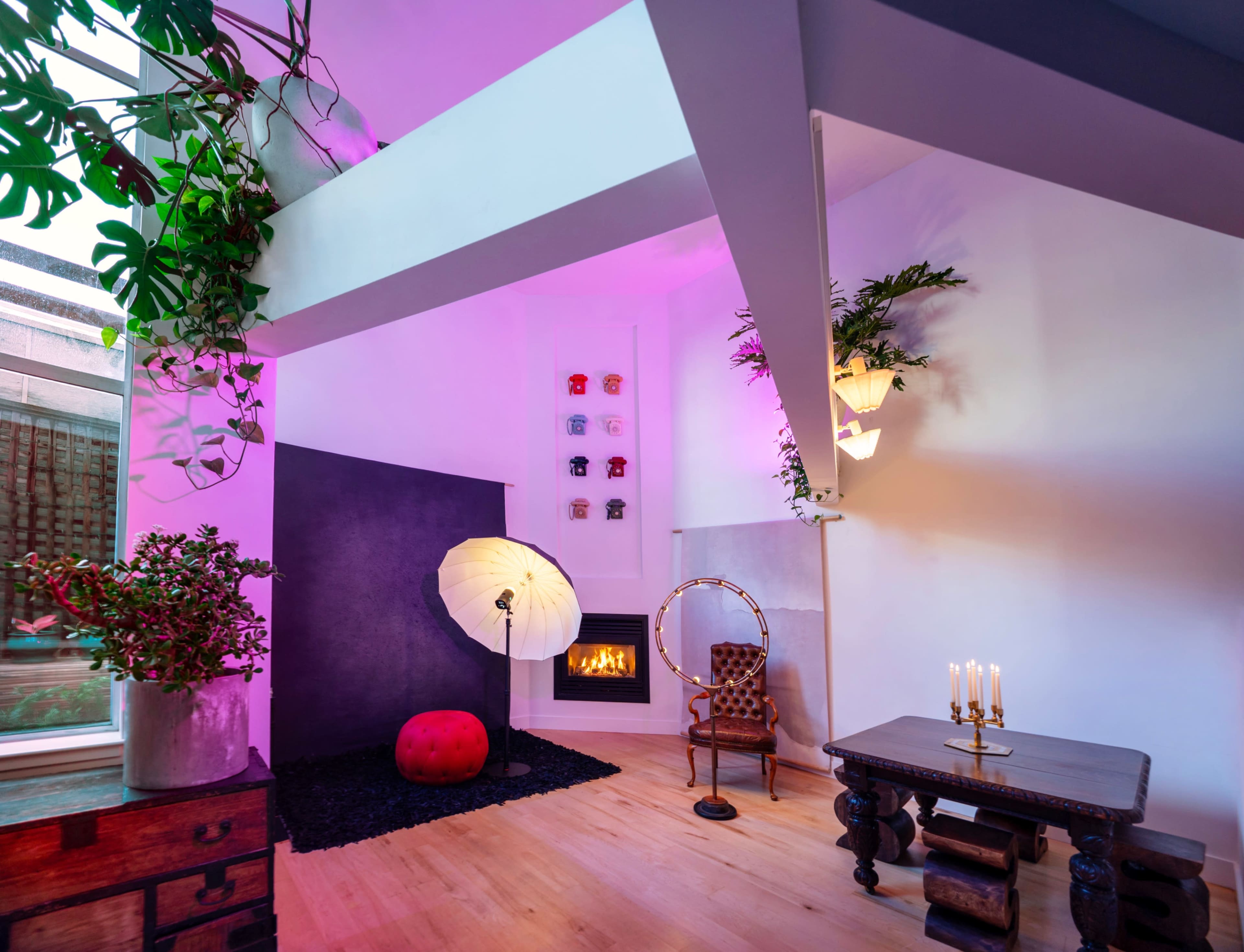 The interior features a modern living space with a fireplace, decorative plants, a circular chair, and contrasting lighting.