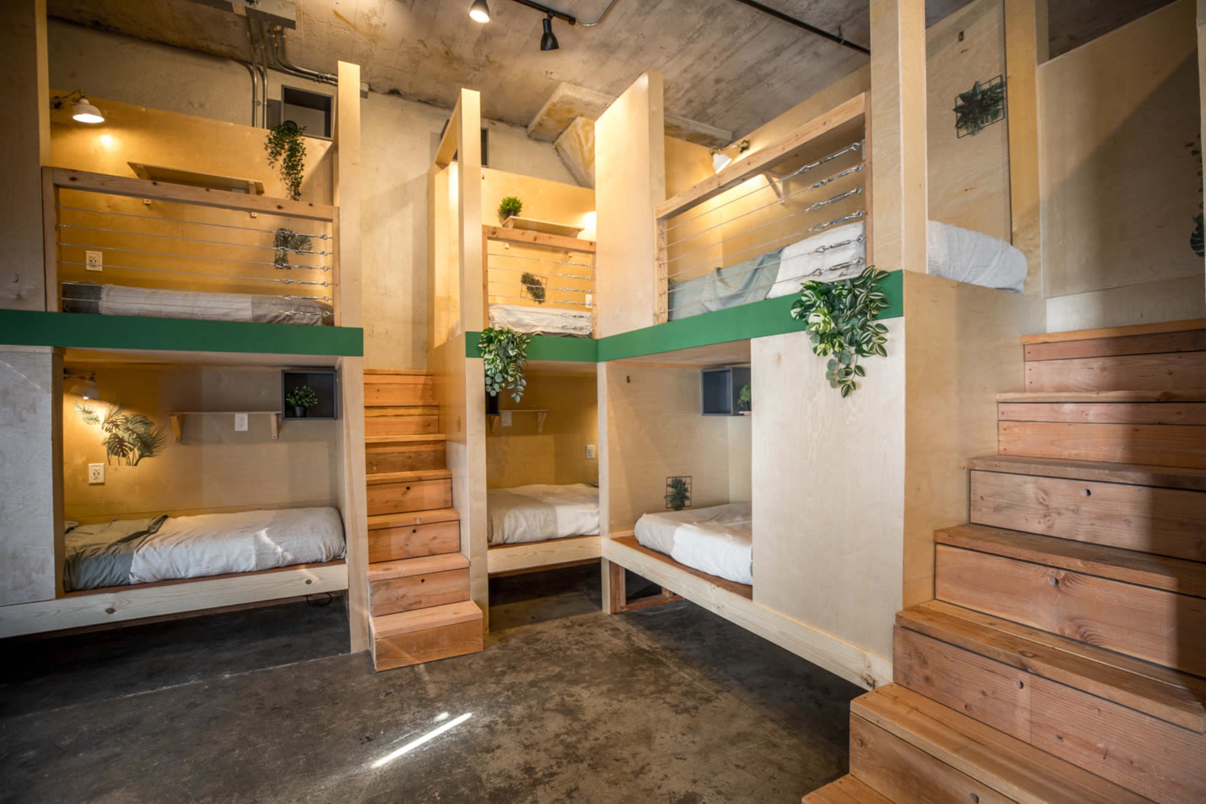 The image shows a modern multi-level bunk room with wooden bunk beds arranged in a spacious interior.