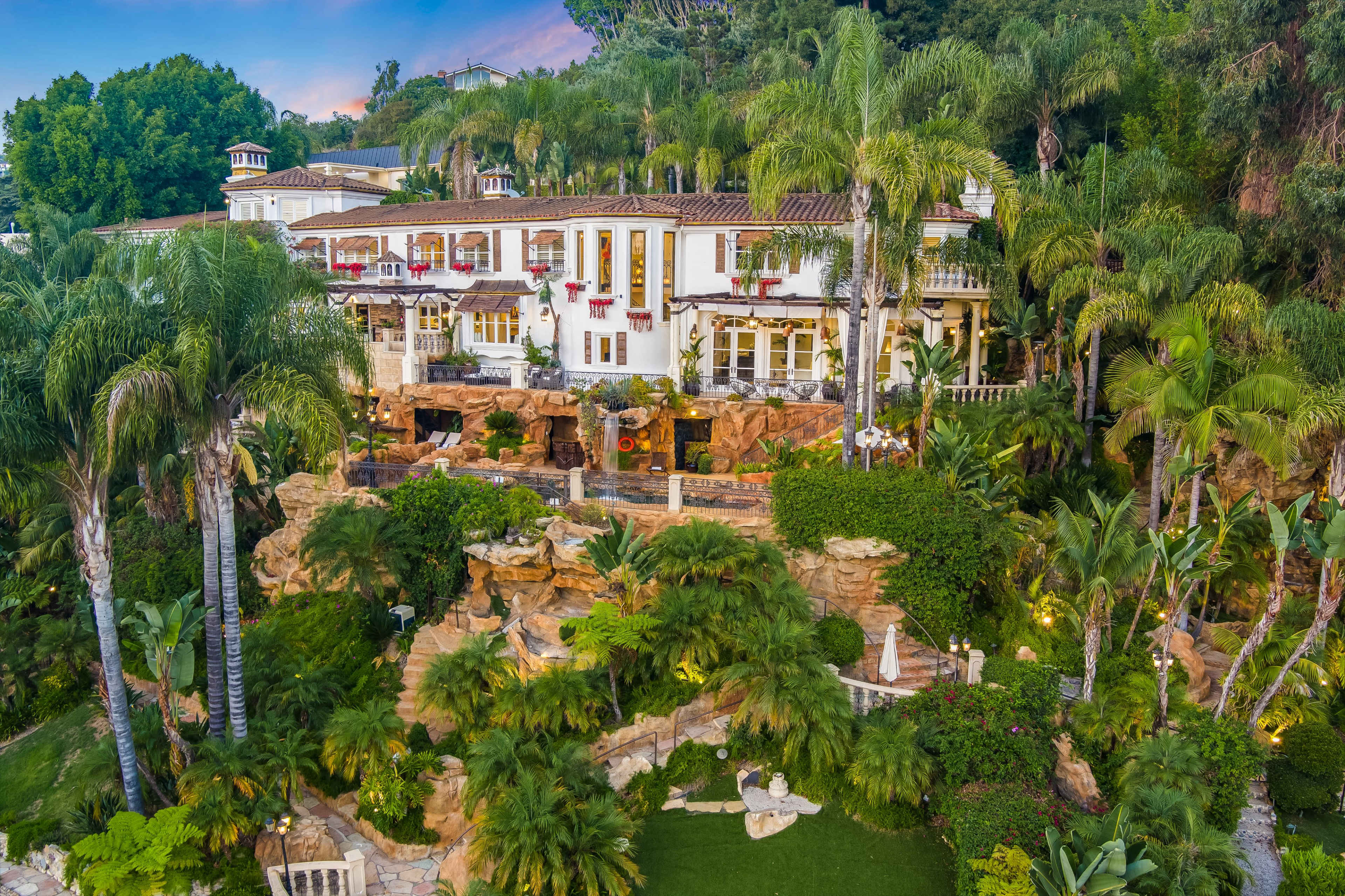 A lavish villa surrounded by lush tropical vegetation and rocky landscaping.