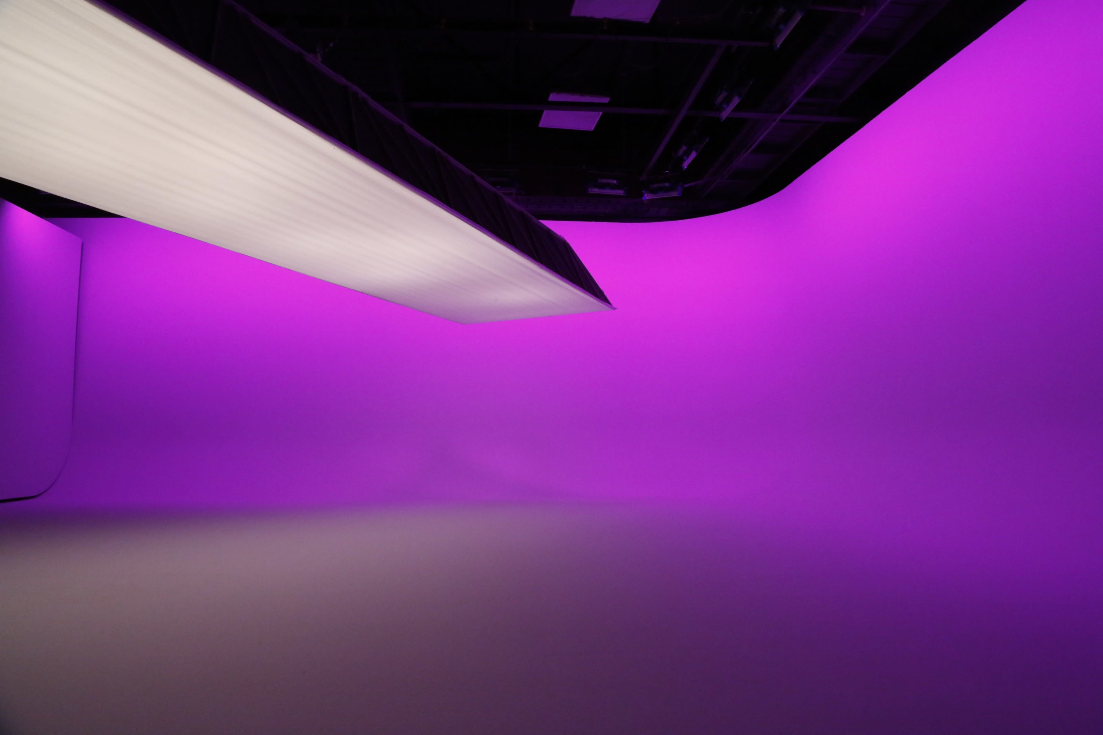 A studio space with a seamless purple backdrop and soft lighting from above.