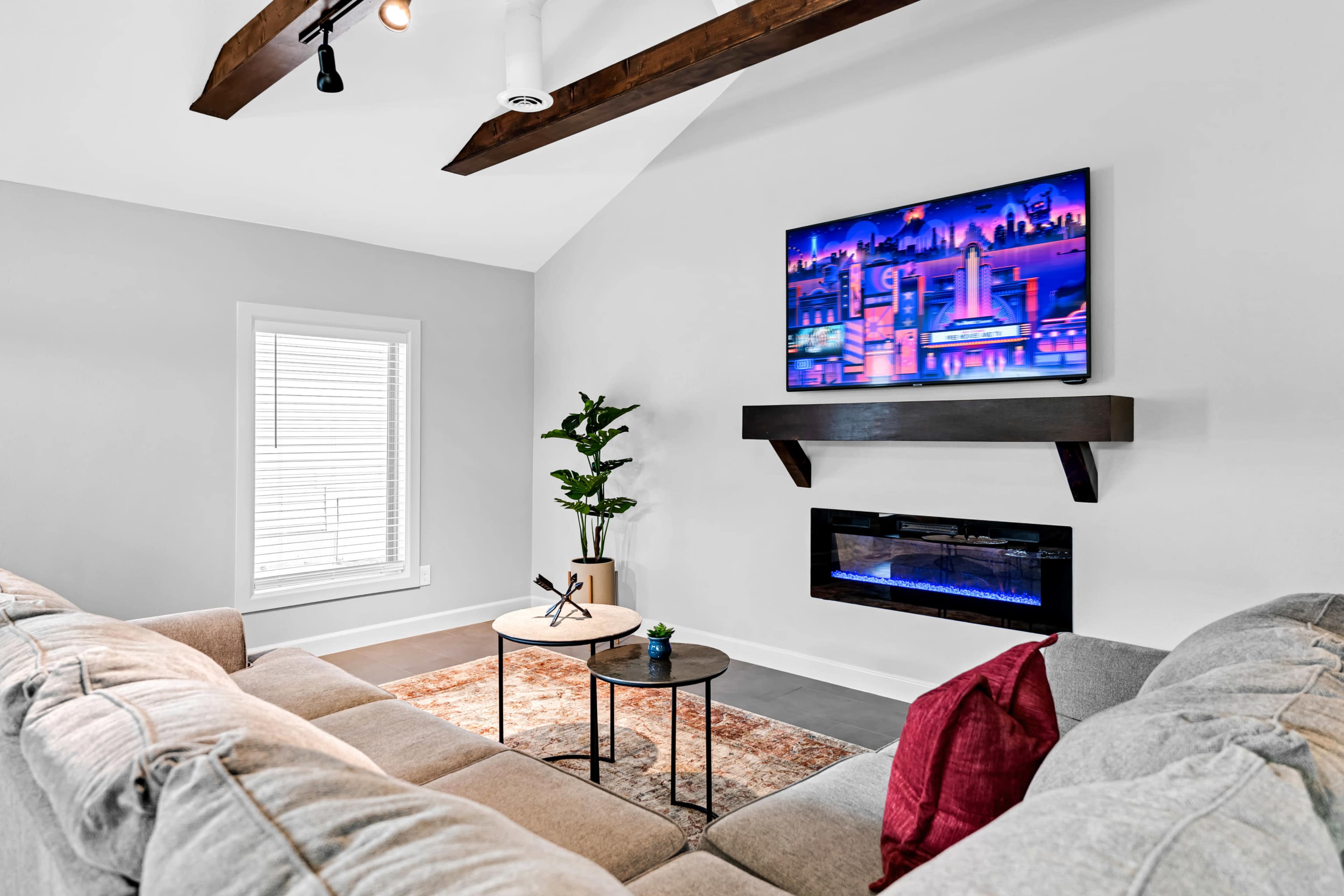 A modern living room features a couch, a small coffee table, and a wall-mounted television above a sleek electric fireplace.