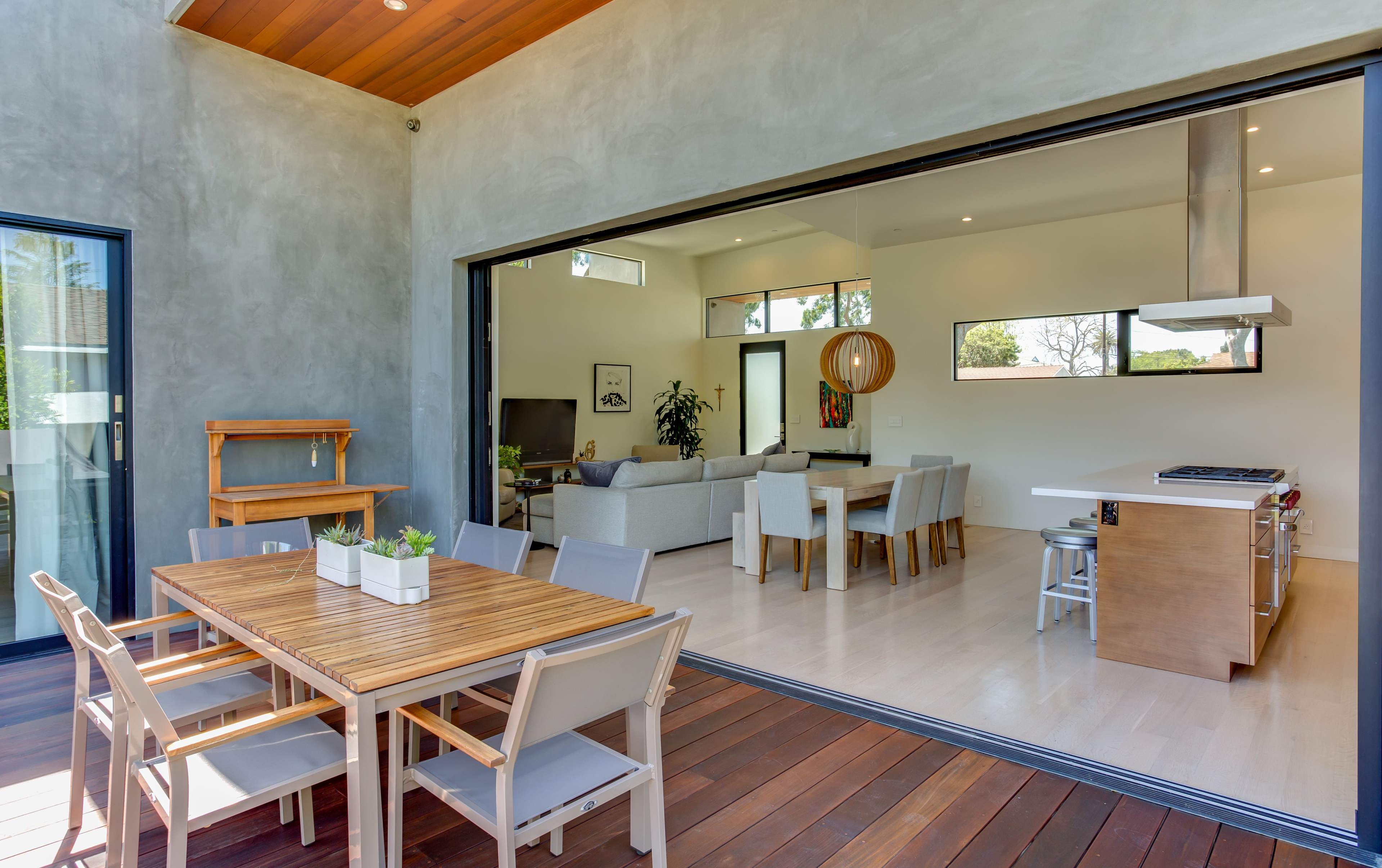 A modern open-concept living space with a dining area featuring a wooden table and chairs, adjacent to a well-lit living room.