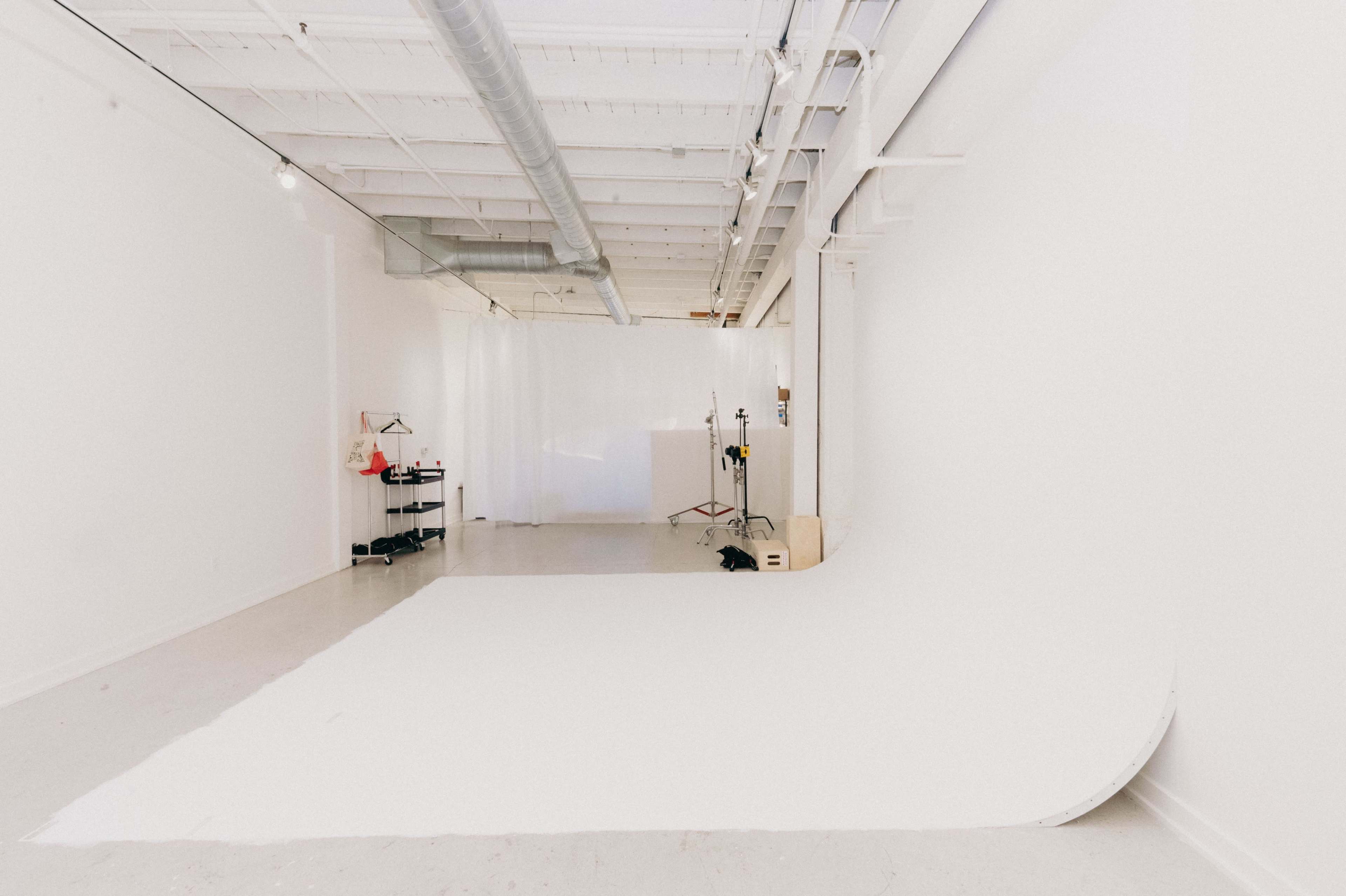A spacious, minimalistic photo studio with white walls and a seamless backdrop.