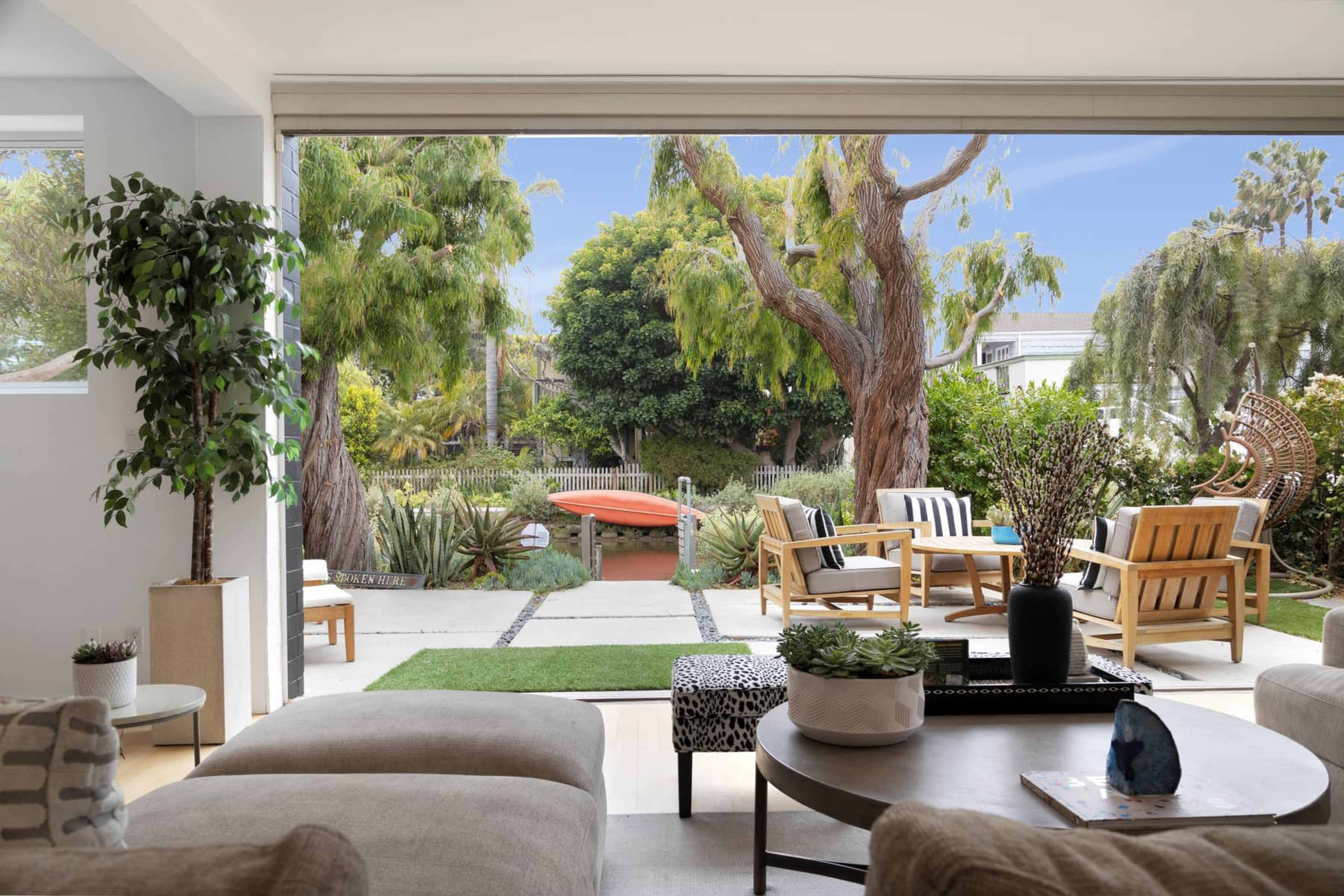 A comfortable living area opens to a landscaped backyard with seating and greenery.
