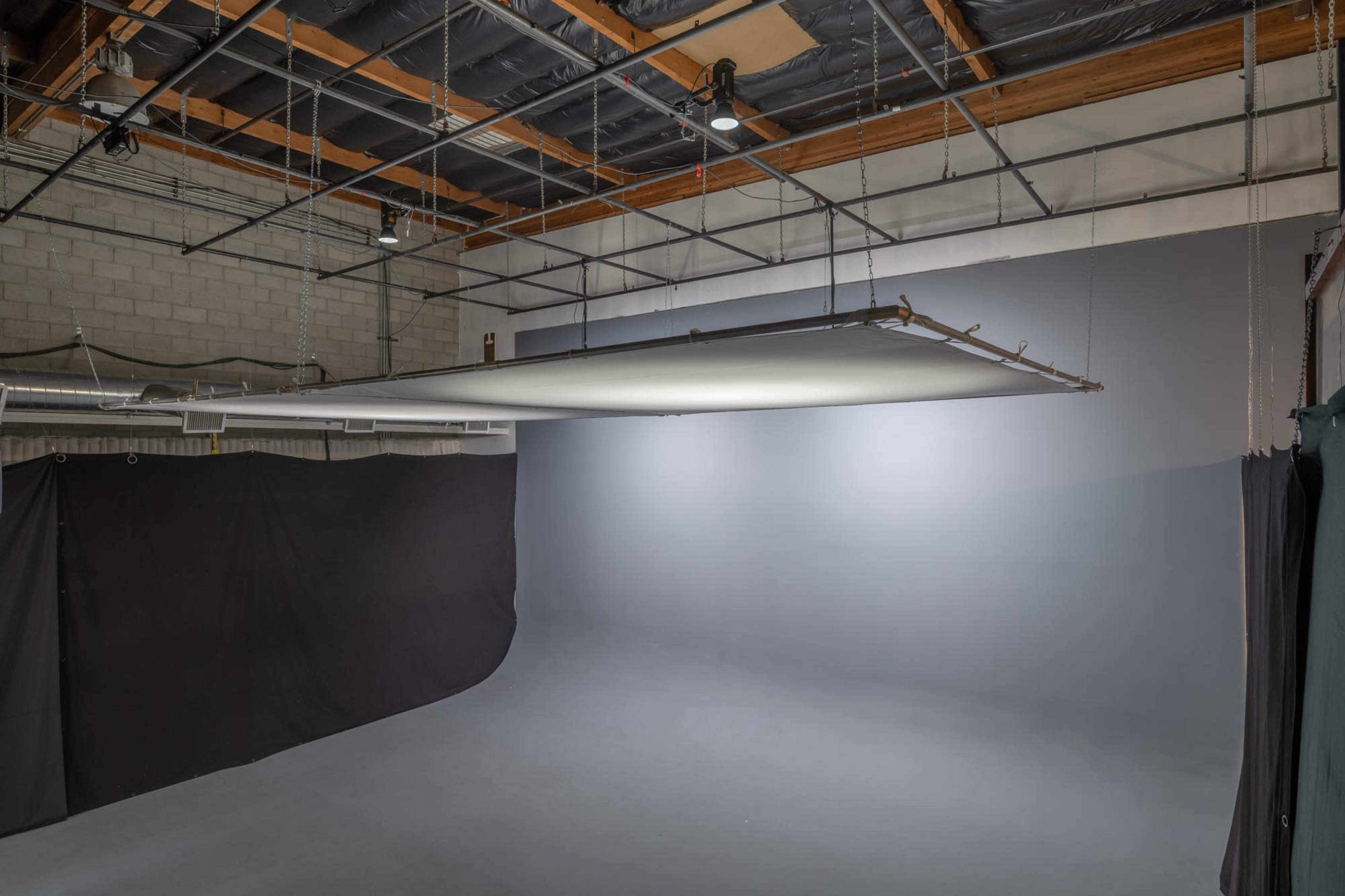 A photography studio with a large overhead light fixture illuminating a seamless backdrop.