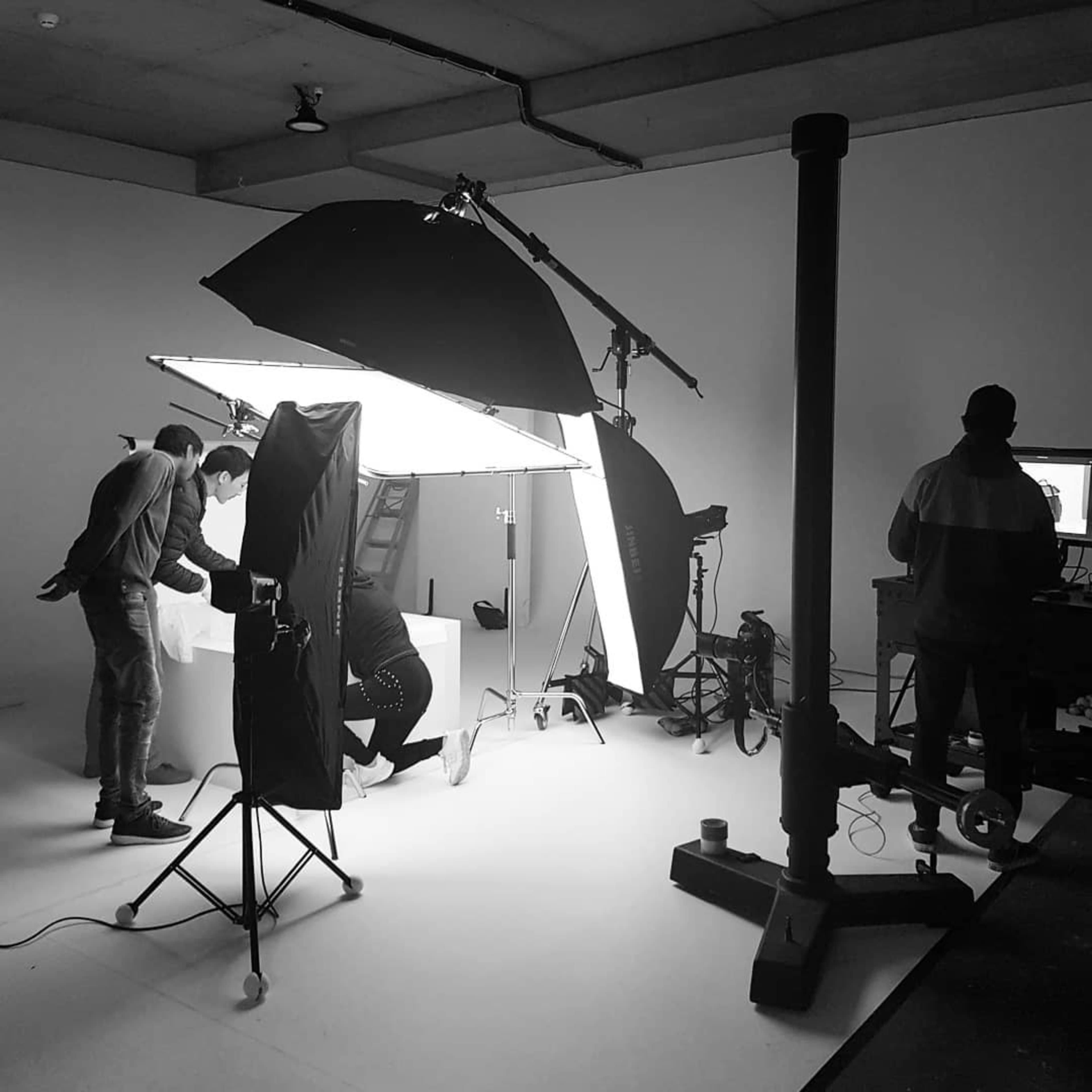 A photography studio setup is shown with multiple light sources and a team working around a backdrop.