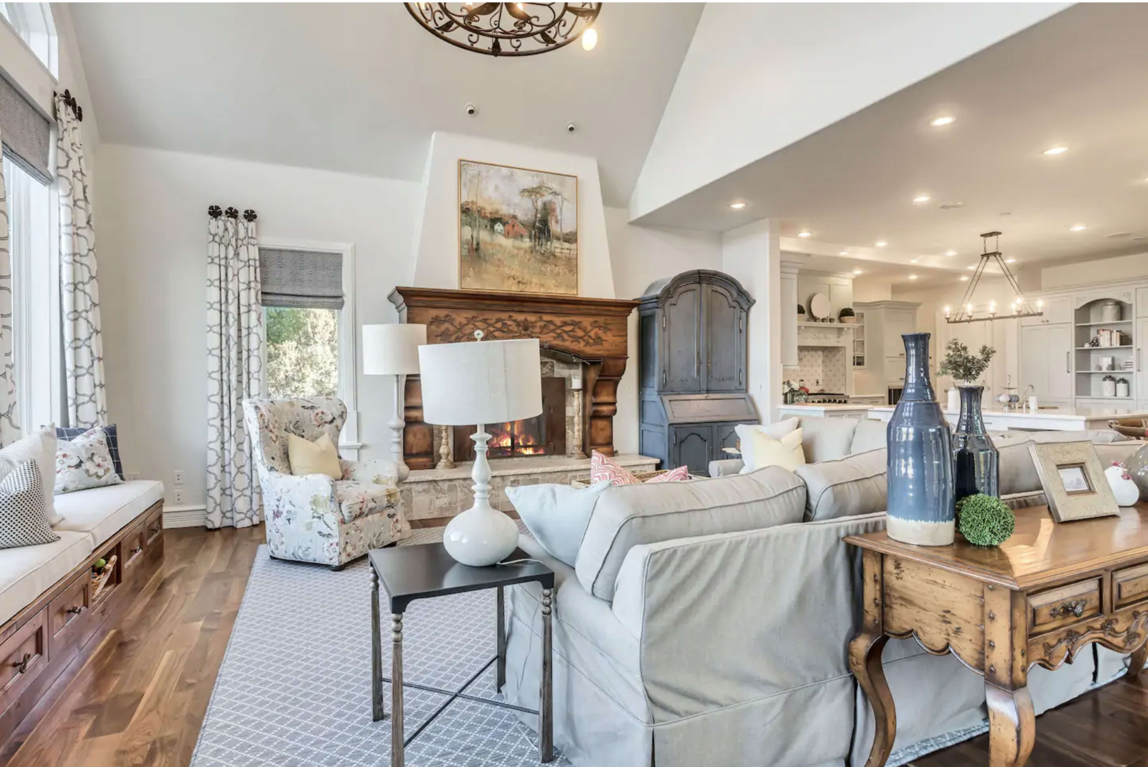 A living room features a stone fireplace, comfortable seating, and large windows letting in natural light.