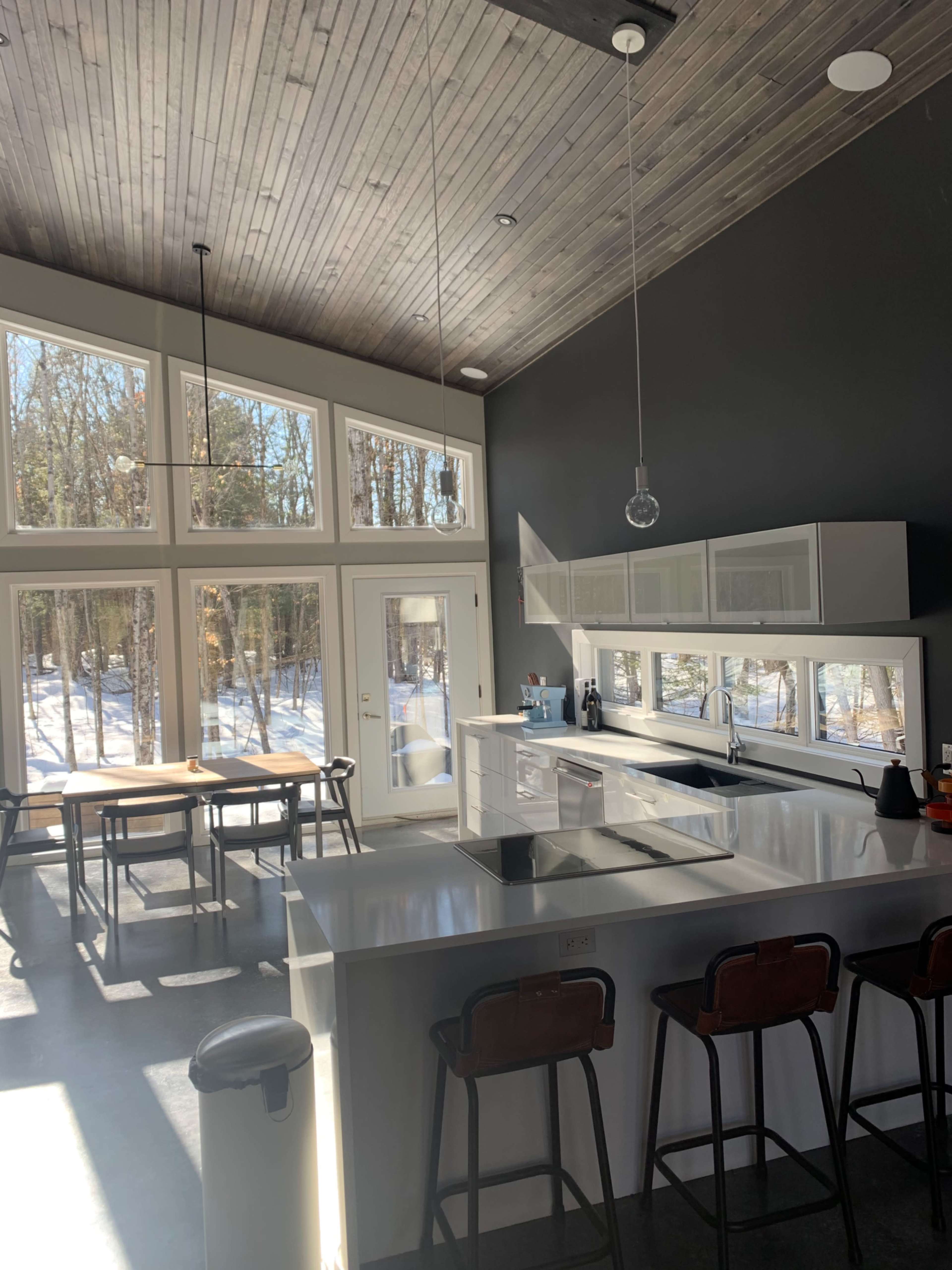 The kitchen features a modern design with a large island, white cabinetry, and ample windows allowing natural light to fill the space.