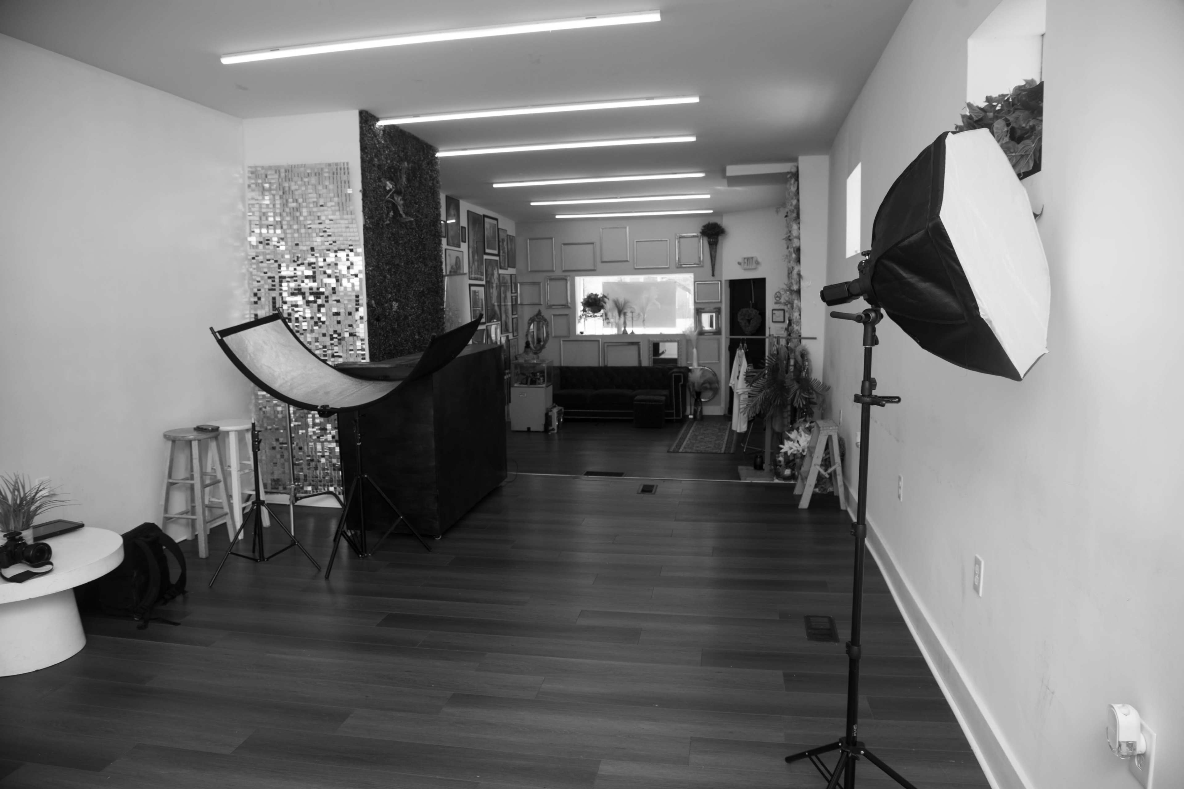 The image shows a spacious room with a reflective wall, studio lighting equipment, and a backdrop setup in a photography studio.